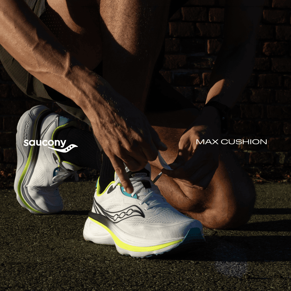 Person tying laces on white running shoes with neon details