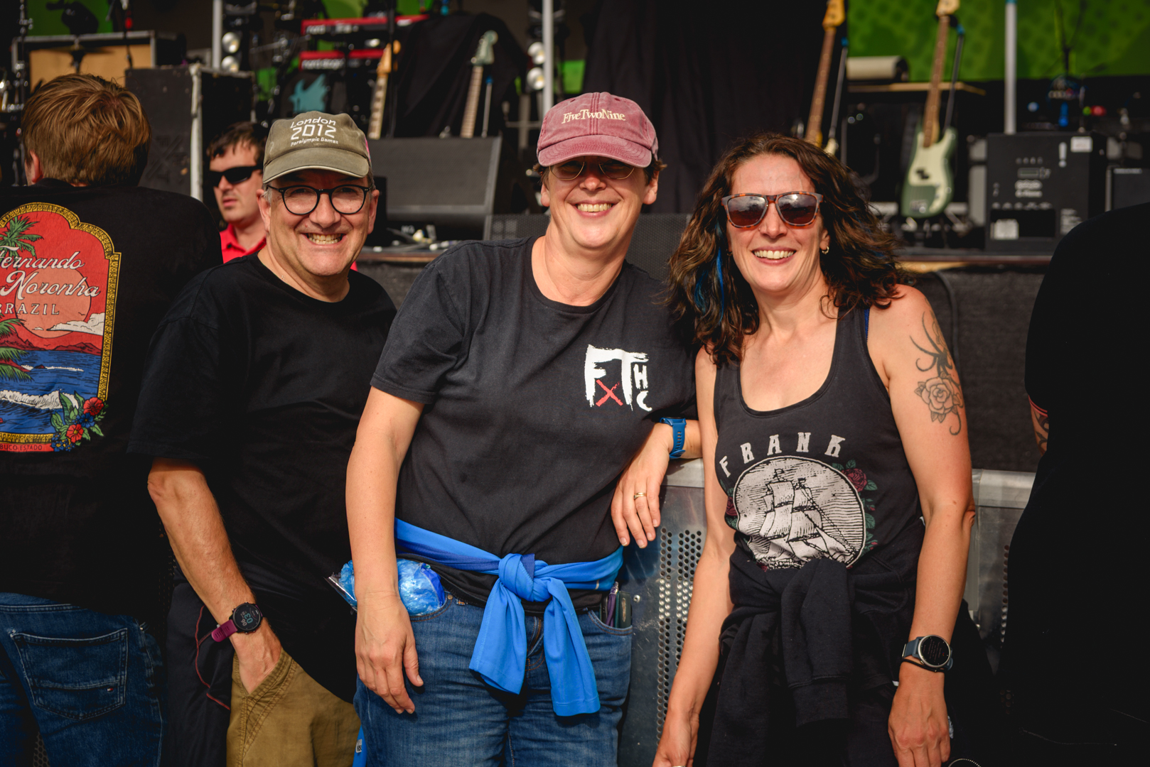 Three people smiling at an outdoor music festival stage