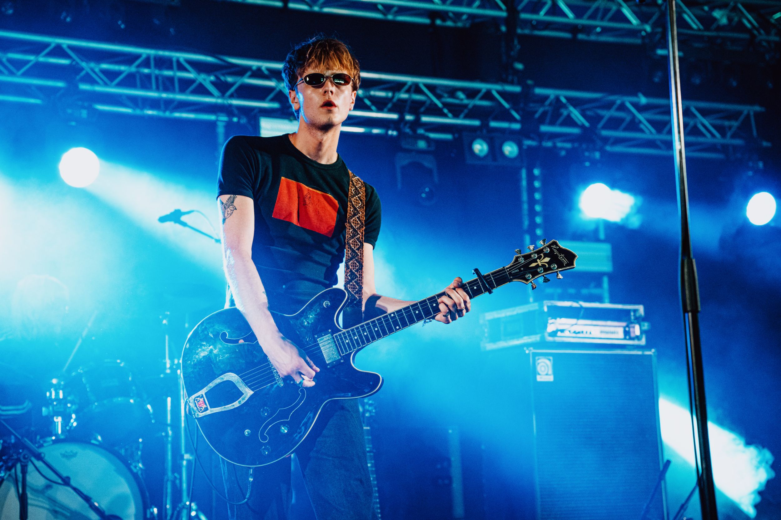 Guitarist in sunglasses performing under blue stage lights
