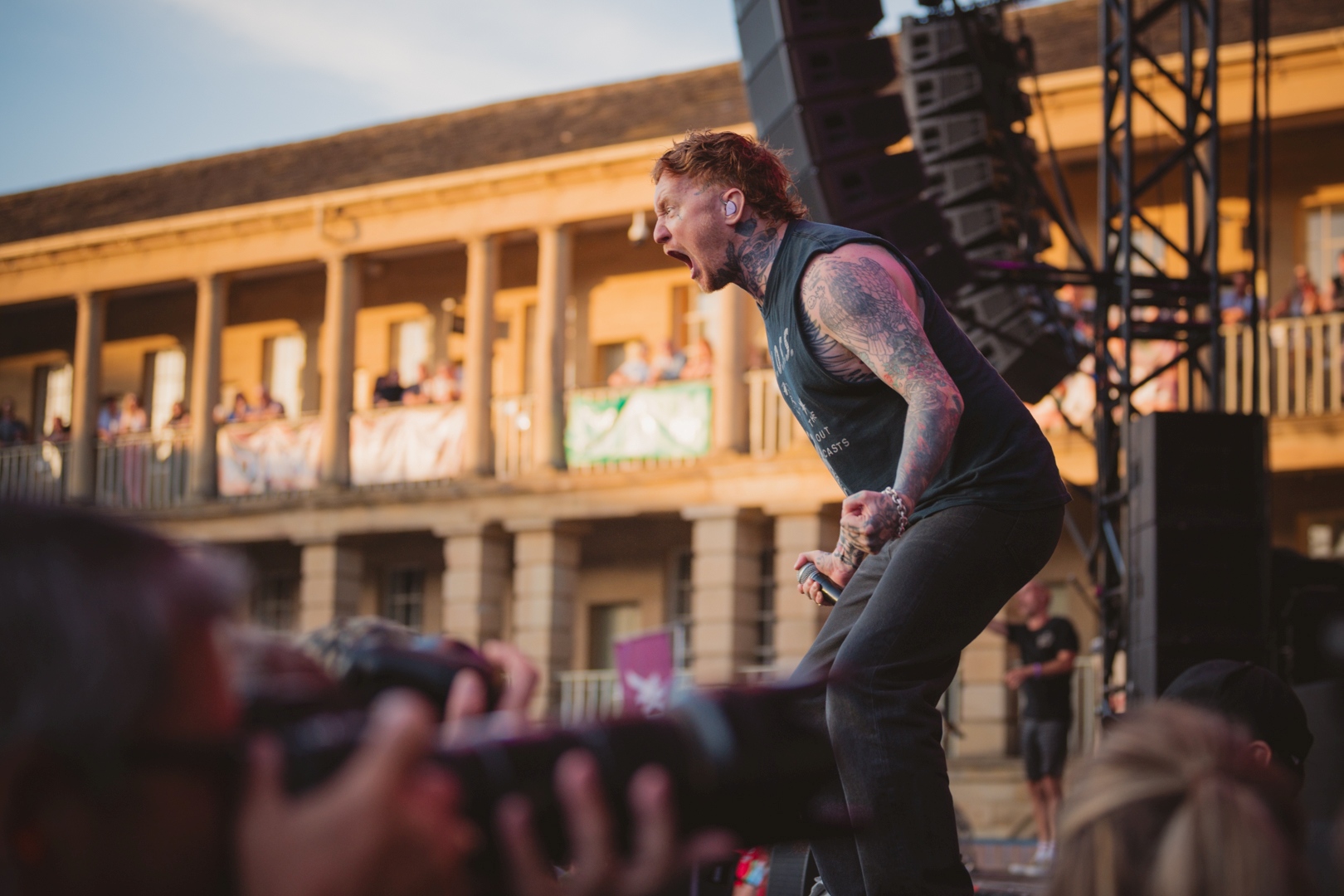 Tattooed singer performing energetically on outdoor stage