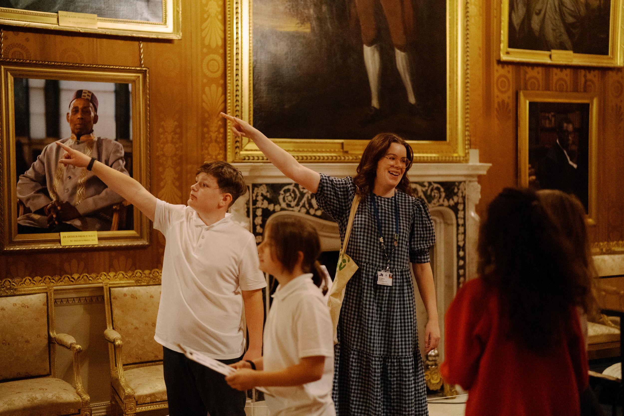 Children and guide in ornate gallery with framed paintings