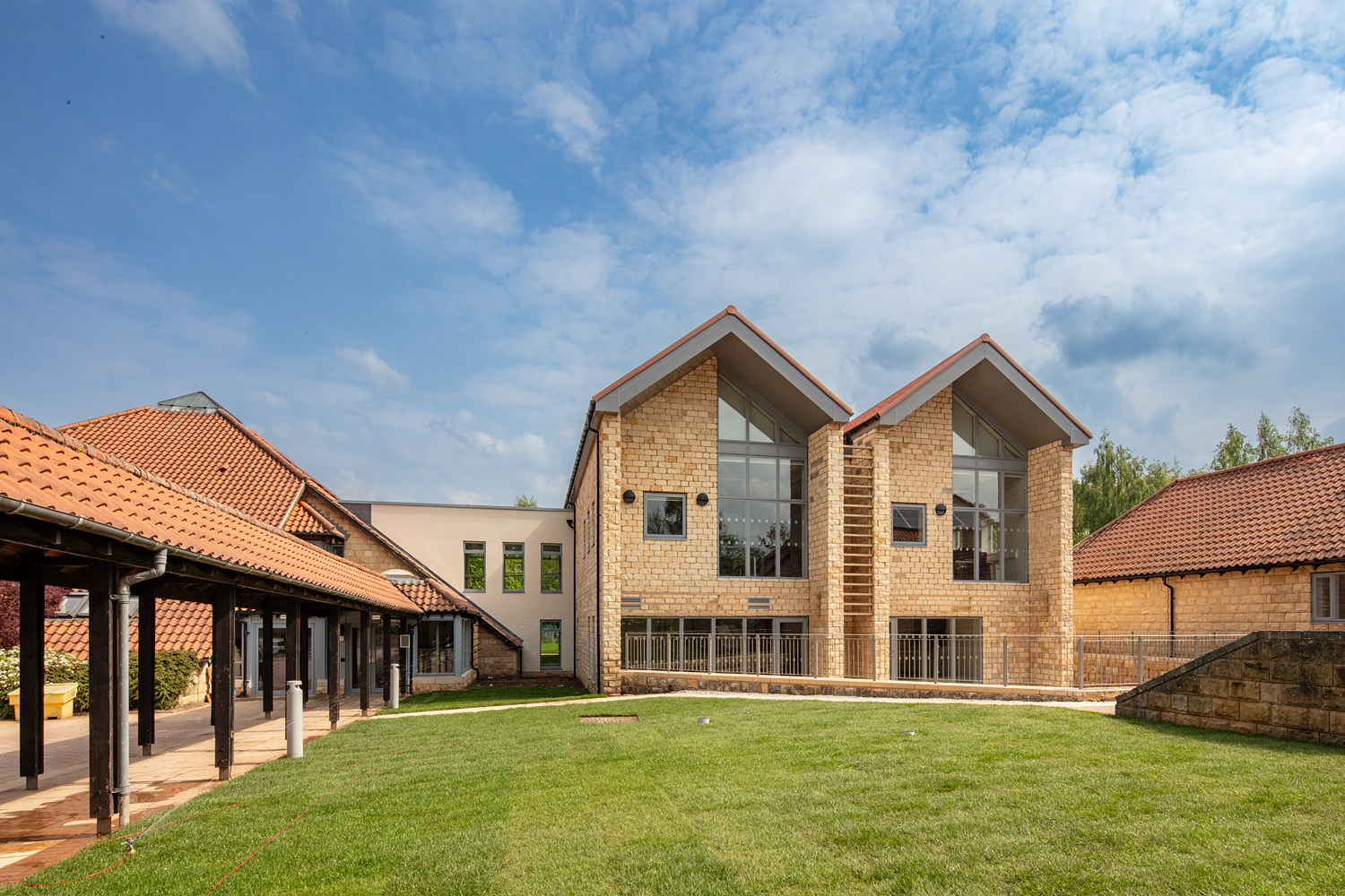 Modern stone building with red-tiled roofs and large glass windows
