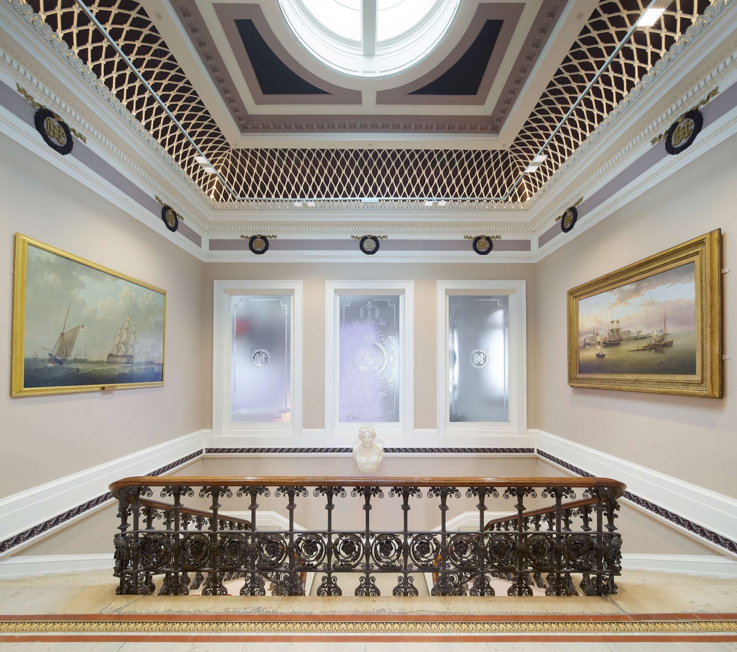Elegant Georgian staircase with ornate iron railing and paintings
