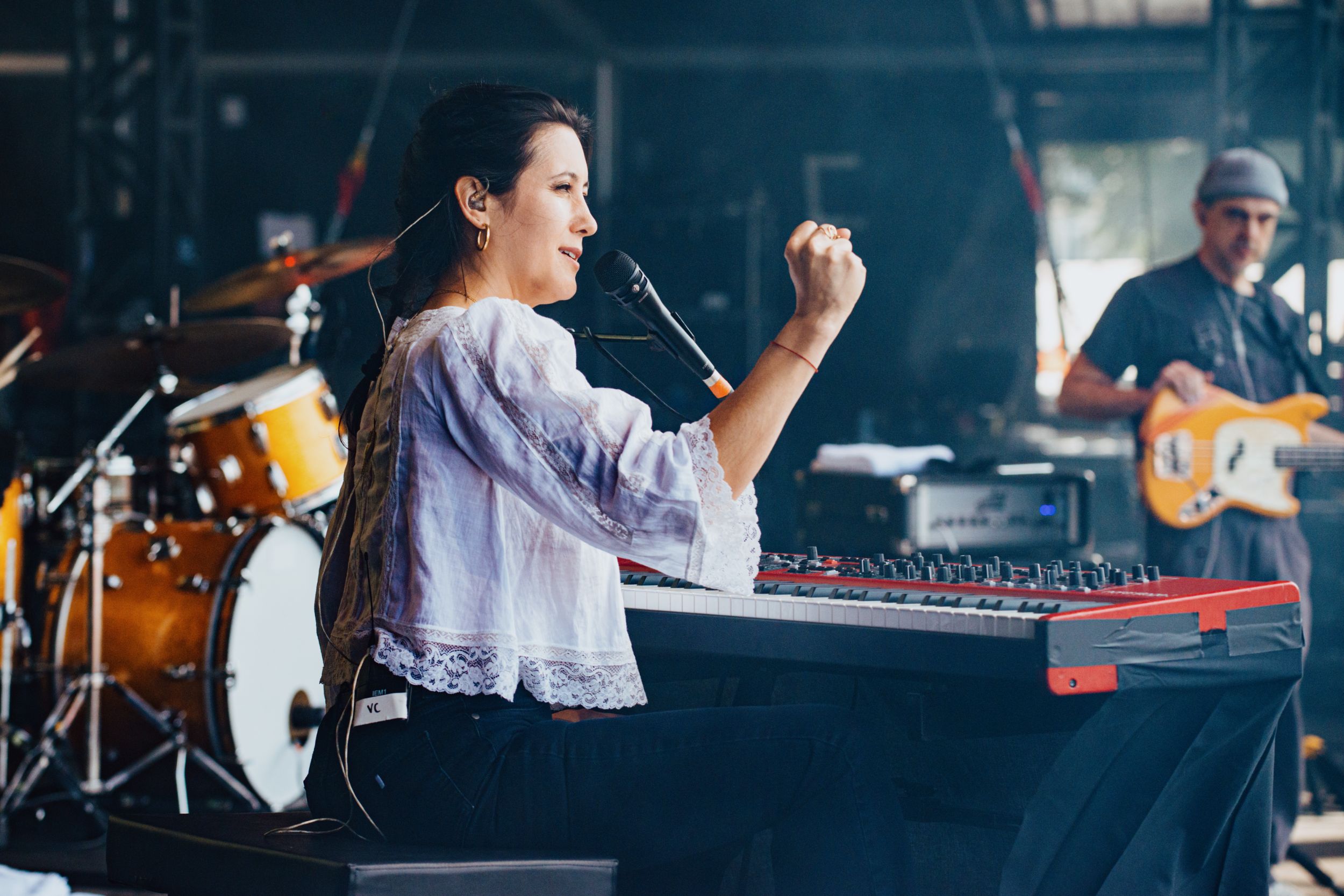 Woman performing at a music festival with a keyboard and band