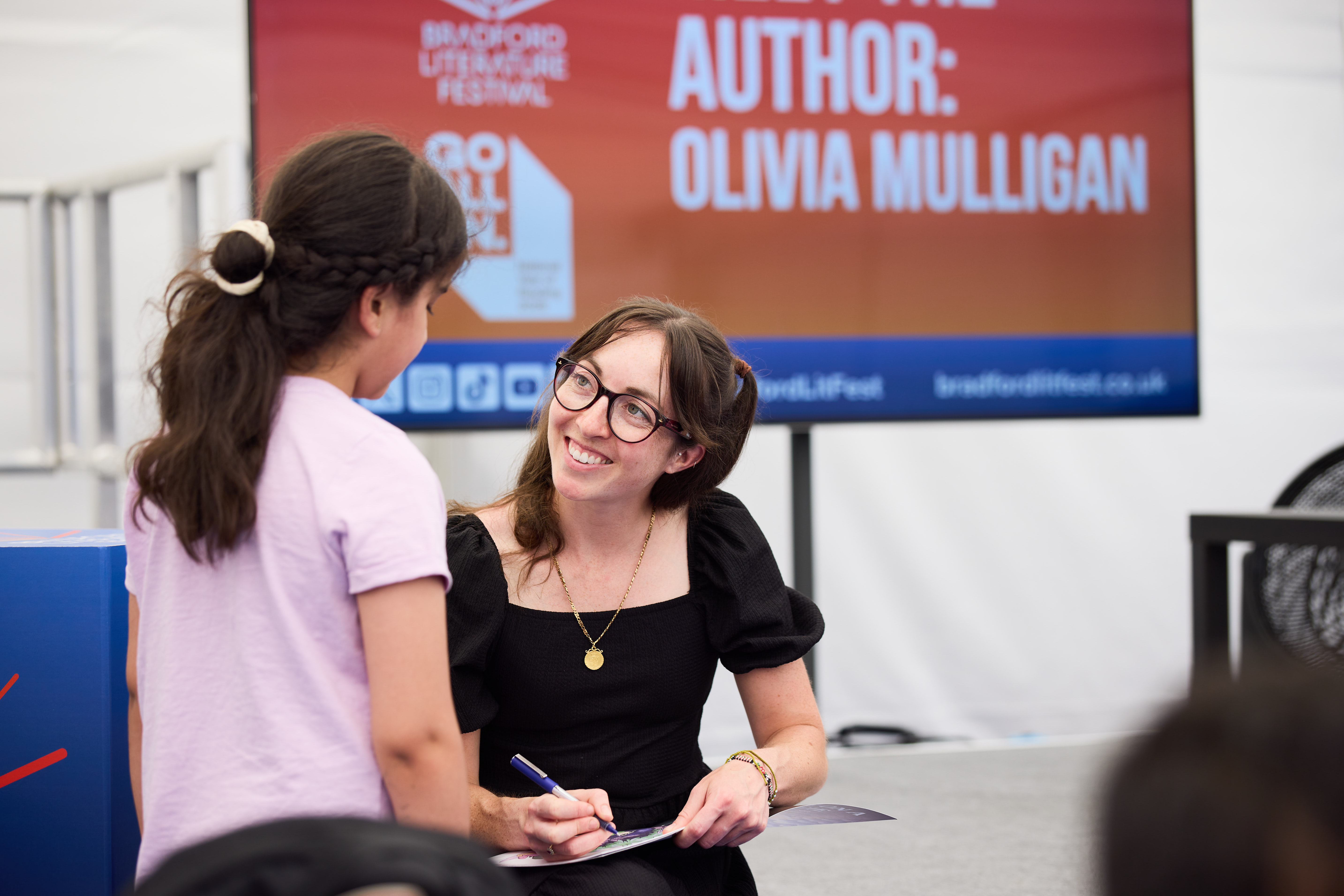 Author signing book for young girl at literature festival