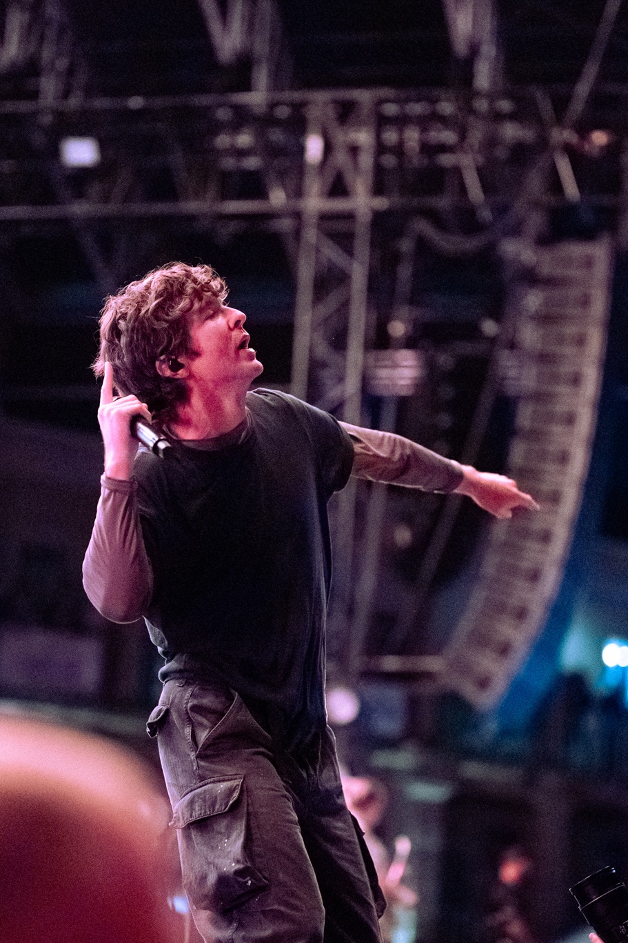 Performer on stage energetically gesturing under bright lights