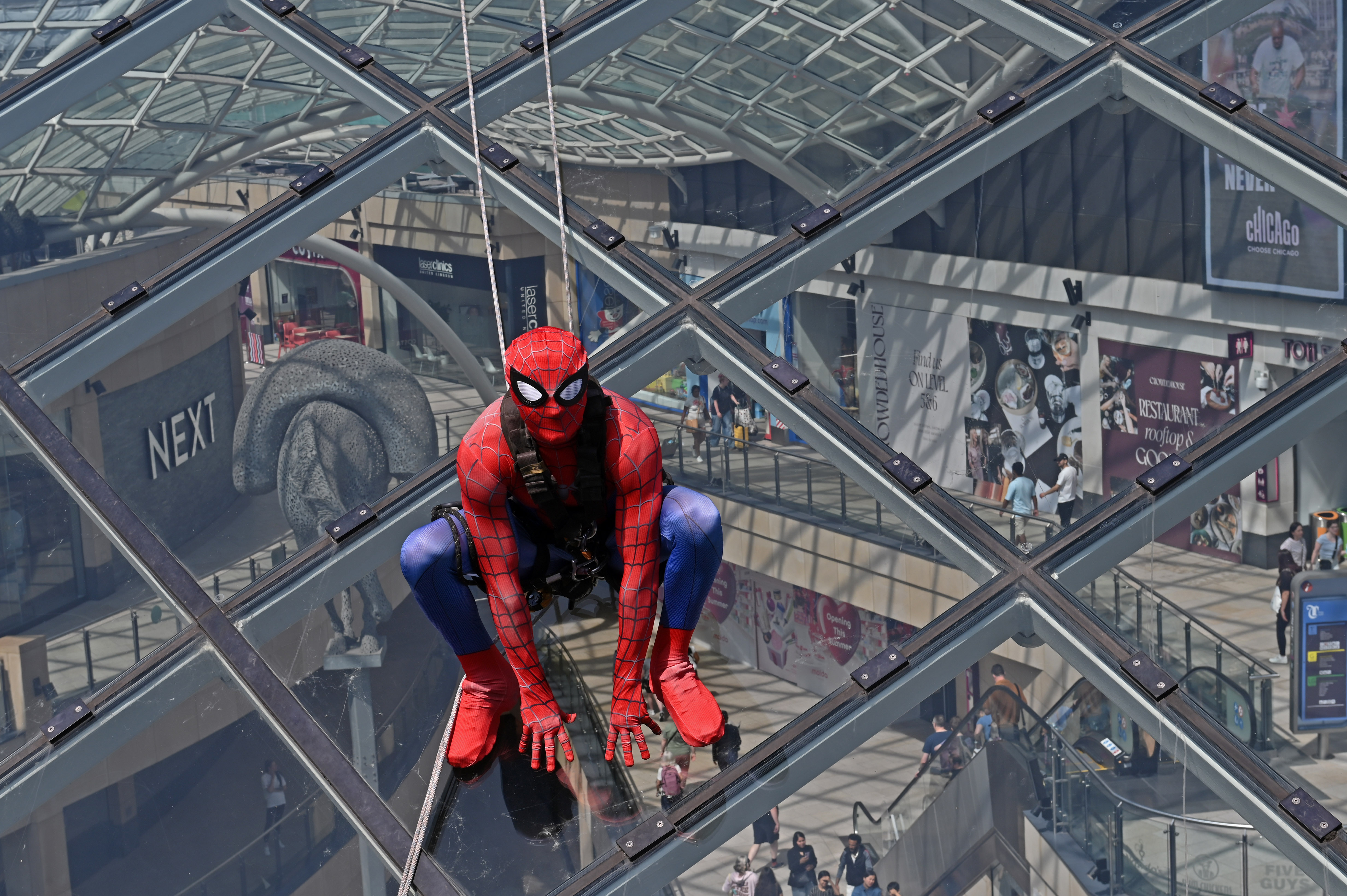 Person in superhero costume climbing glass pyramid roof