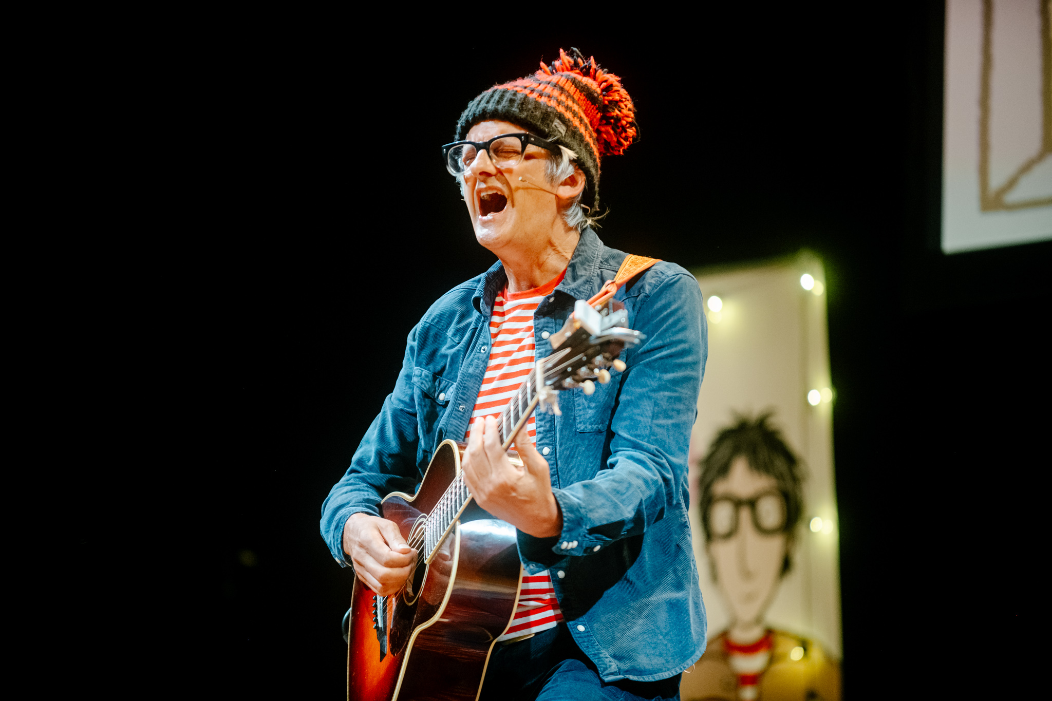 Musician with guitar wearing striped shirt and beanie