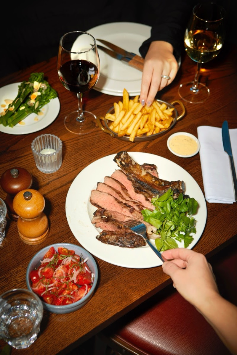 Dining table with steak, chips, salad, and glasses of wine