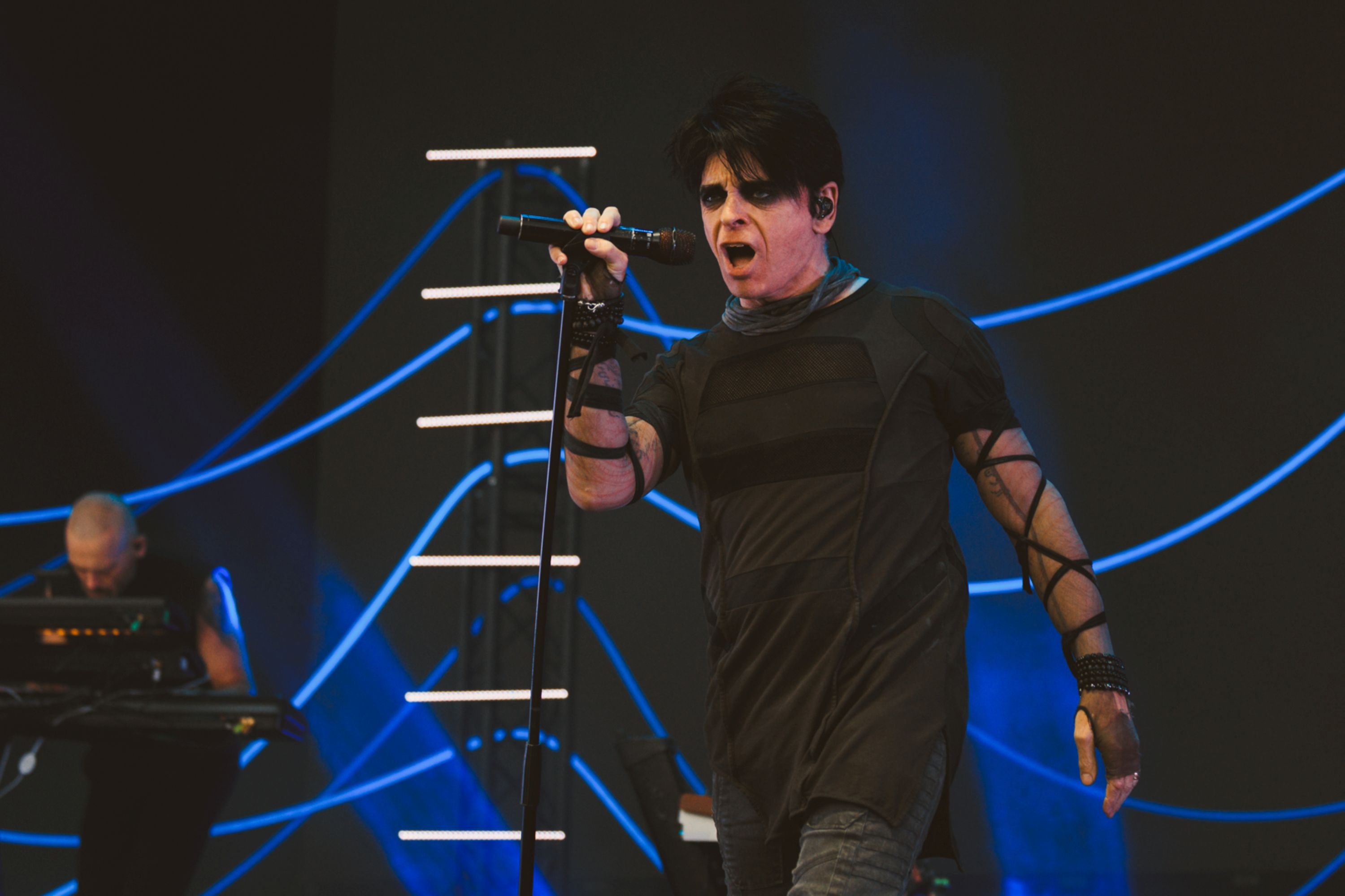Singer performing on stage with blue lights and microphone