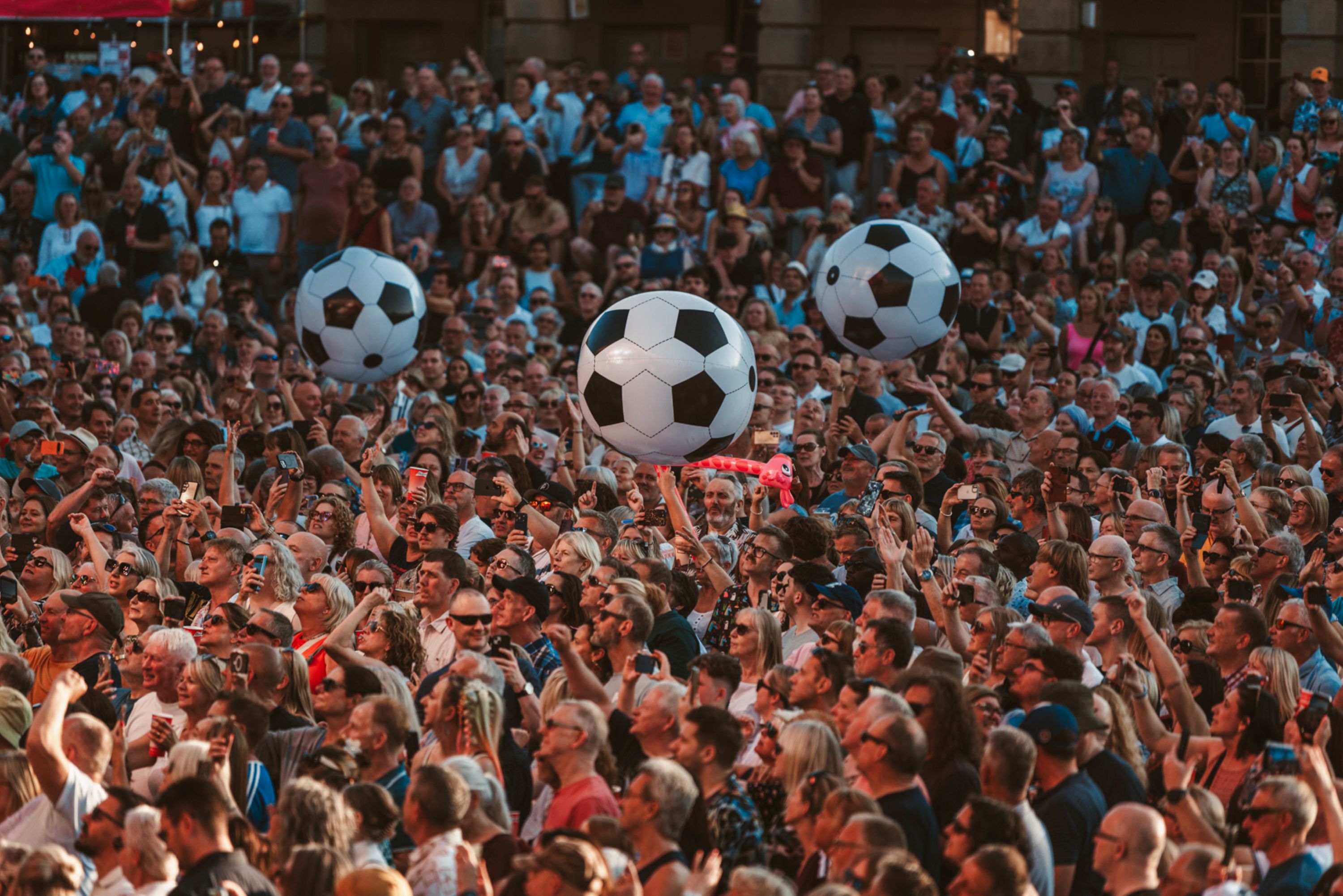 Crowd at outdoor festival with giant soccer balls