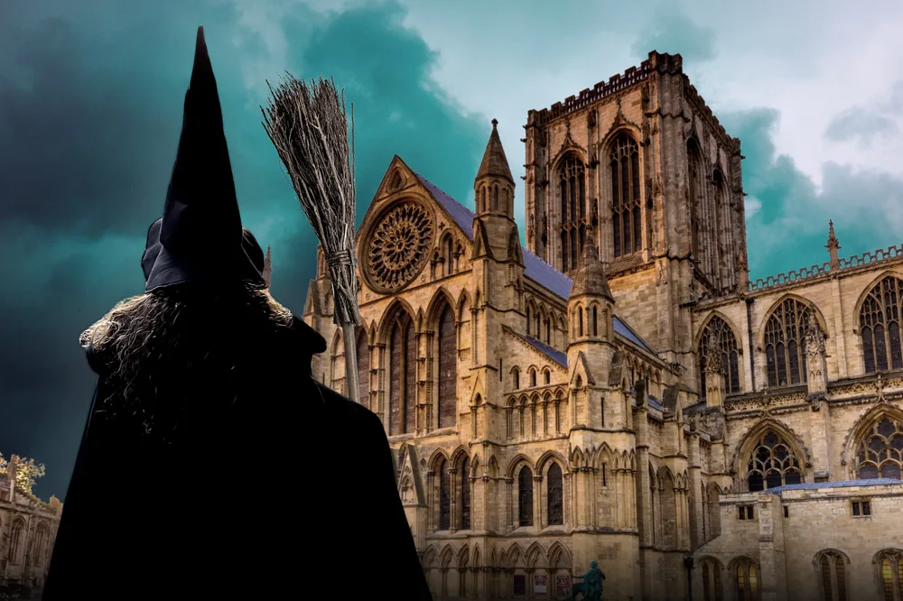 Person in witch costume stands before York Minster under moody sky