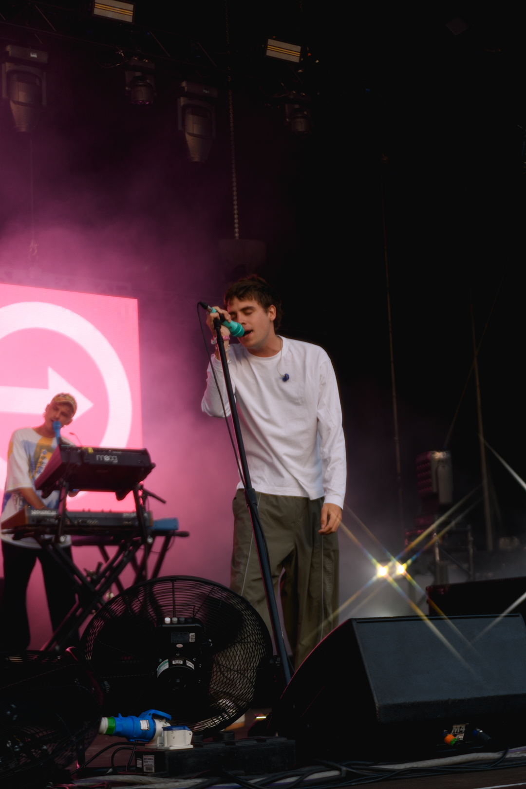 Musician singing on stage with pink backdrop and keyboard