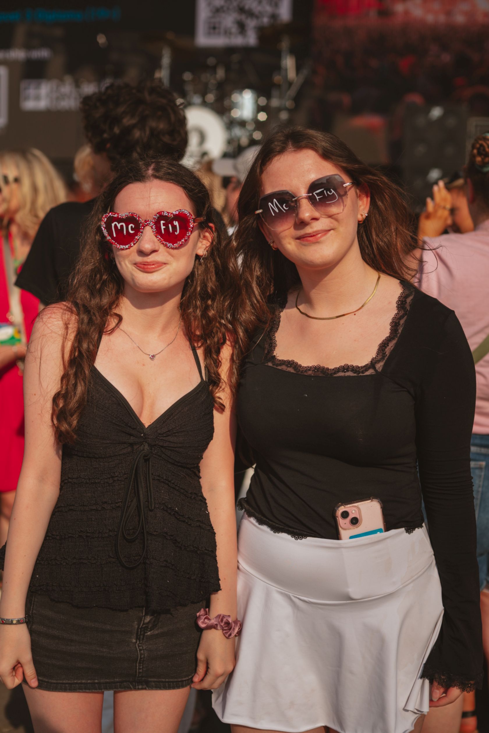 Two women wearing heart-shaped sunglasses at outdoor festival