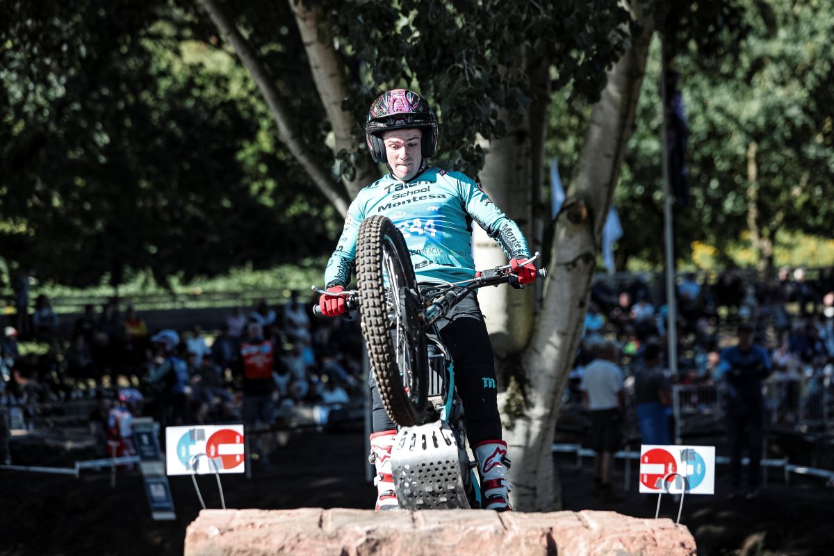 Motorcycle trials rider balancing on rear wheel on rocky terrain