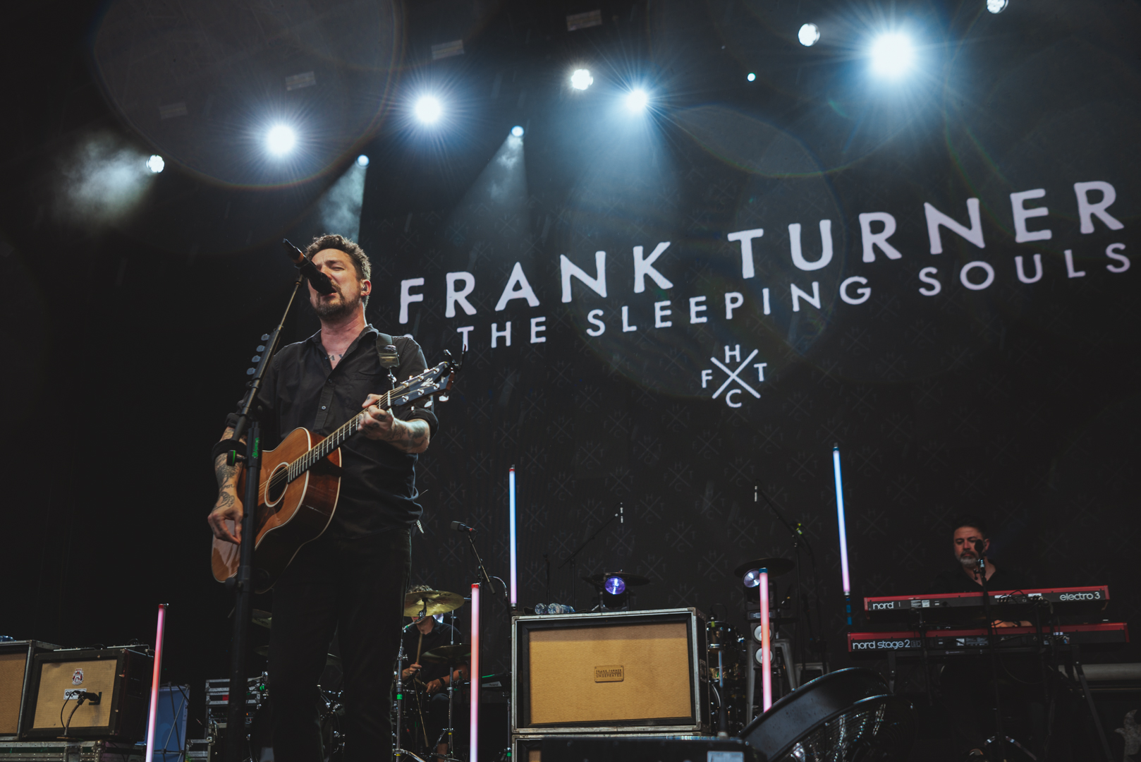 Musician performing on stage with guitar under spotlights