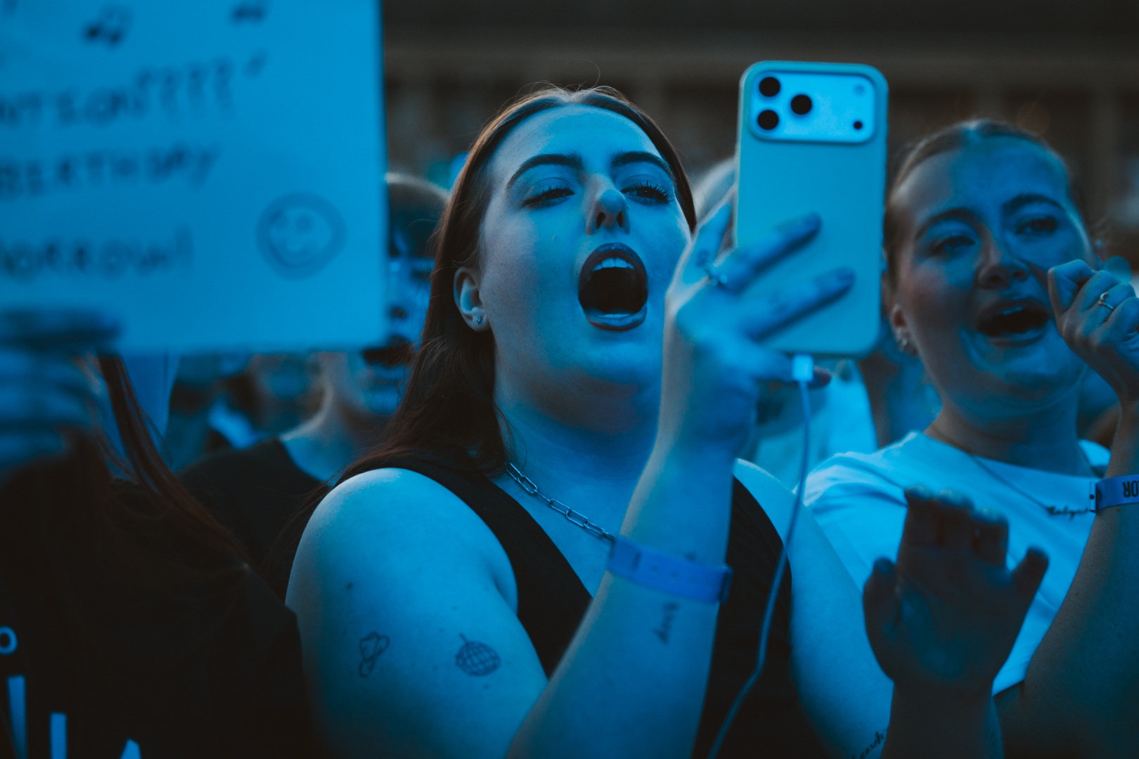 Excited crowd at an outdoor event in Yorkshire, woman filming