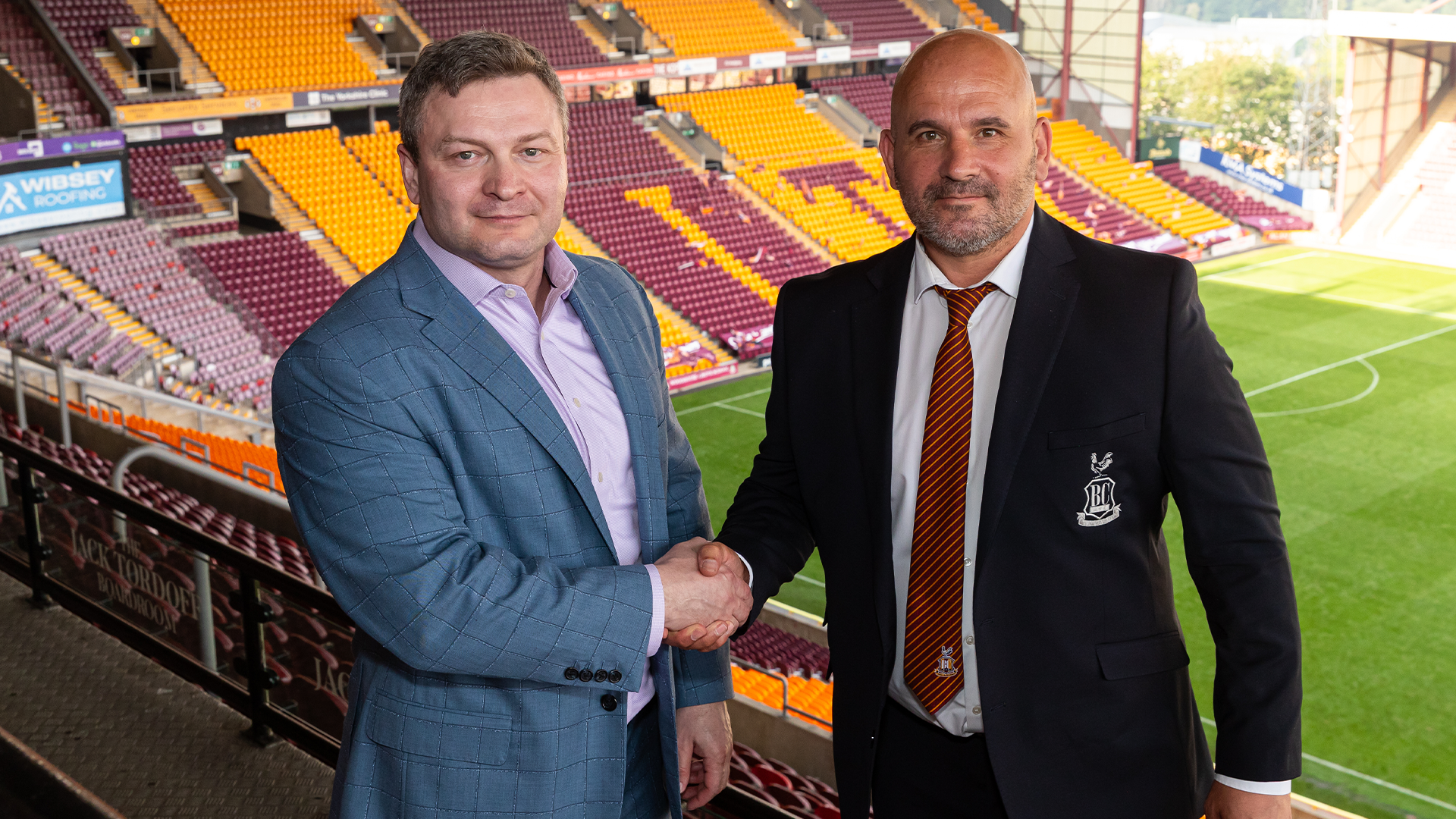 Two men in suits shaking hands at Bradford City stadium