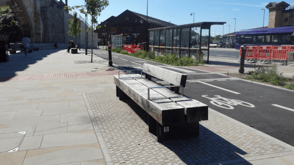Modern stone and metal bench near bus station in urban setting
