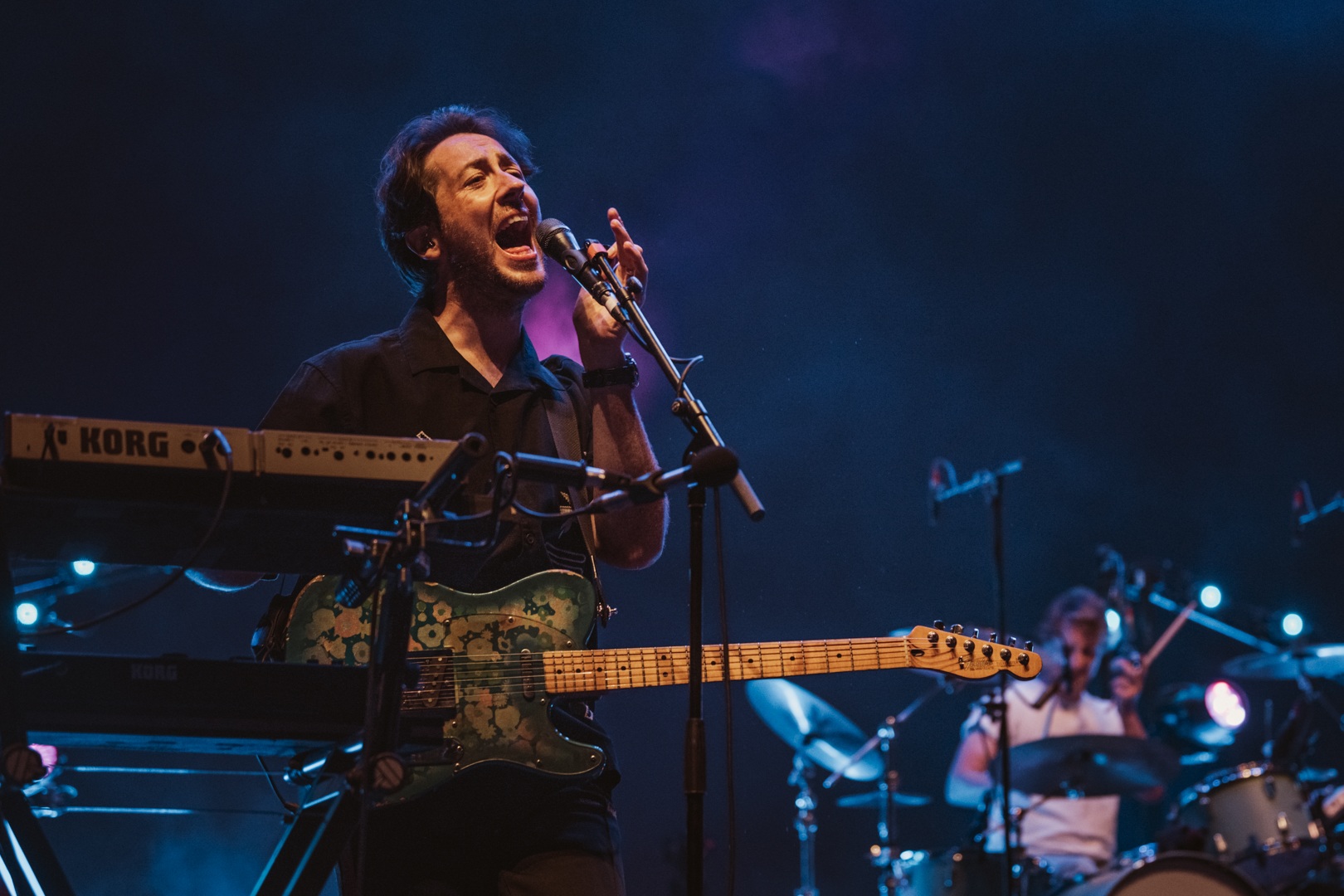 Musician passionately singing on stage with electric guitar