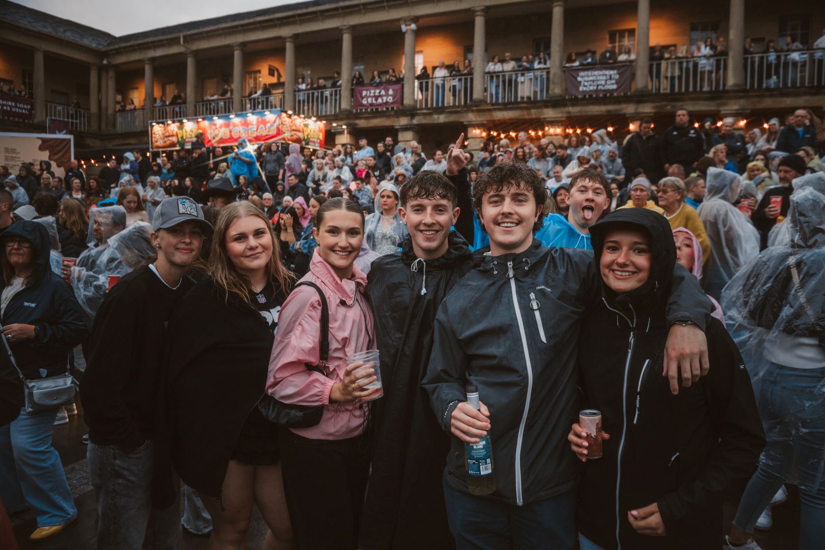 Group of friends in raincoats enjoying a festival crowd