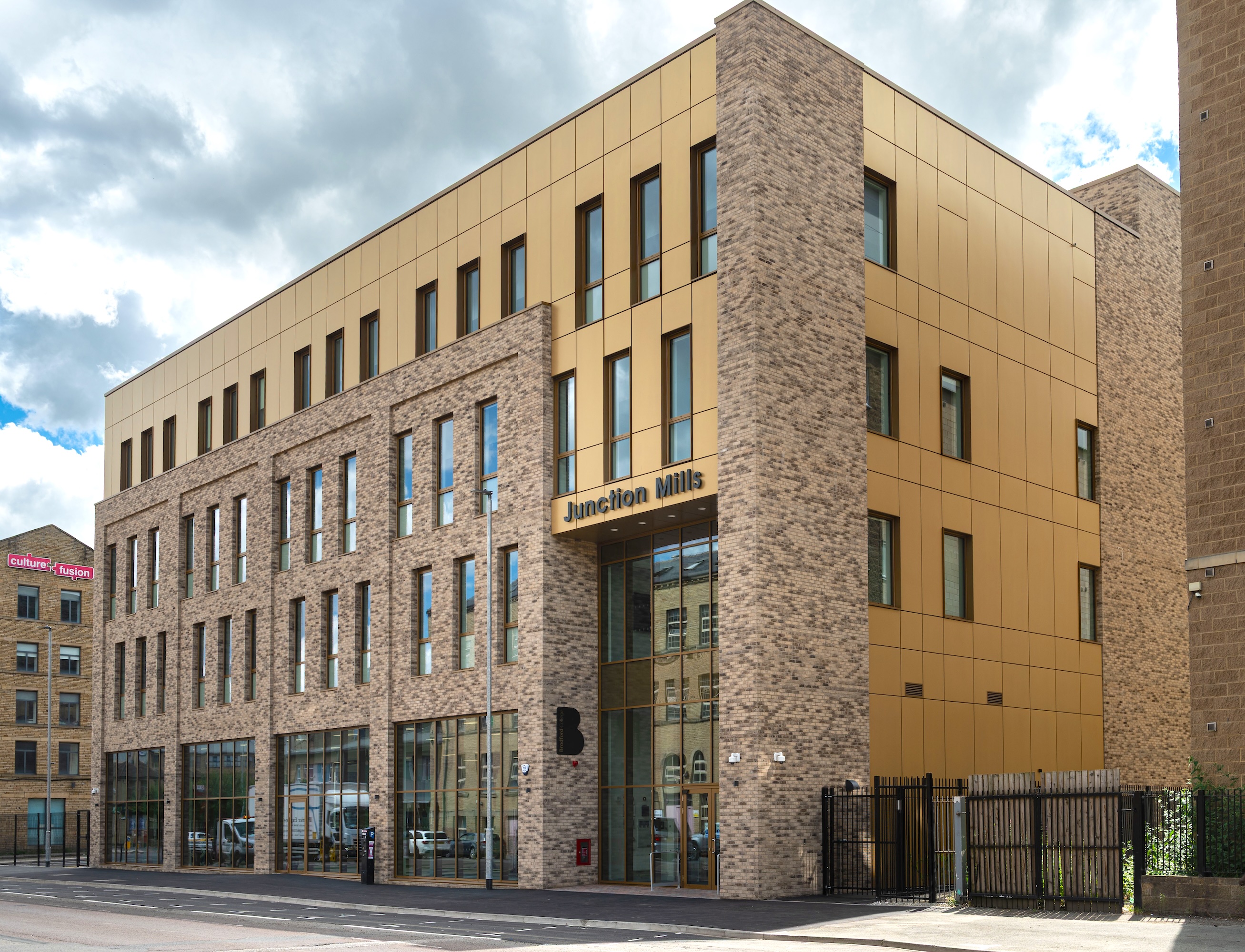 Modern brick and gold building with large windows in urban setting