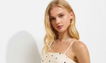 Person with long blonde hair wearing a white polka dot dress