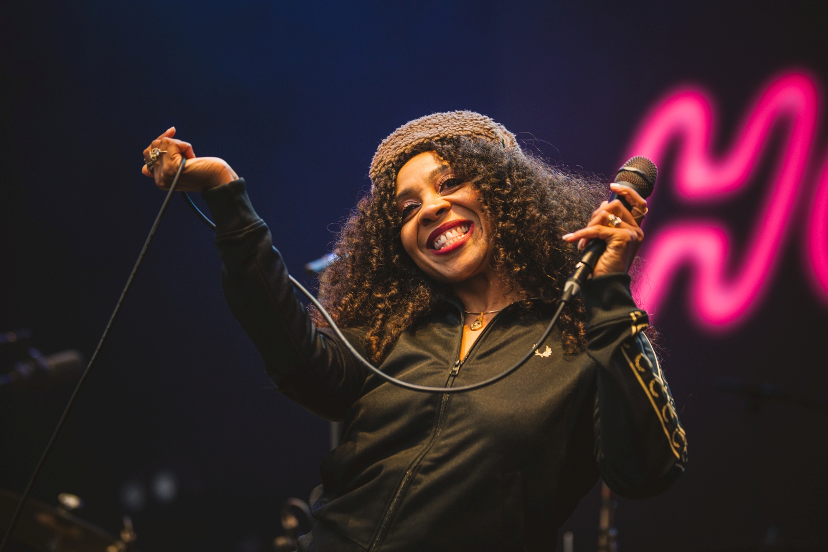 Smiling performer on stage with microphone and neon lights