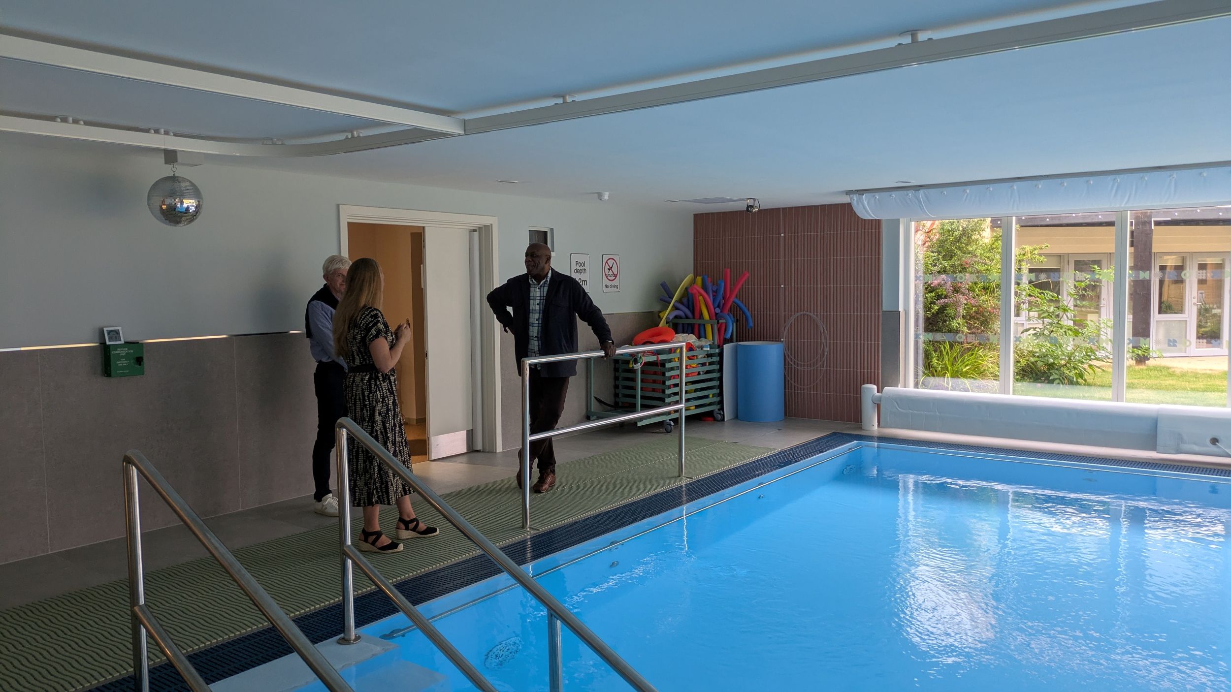 Indoor swimming pool with three people talking nearby