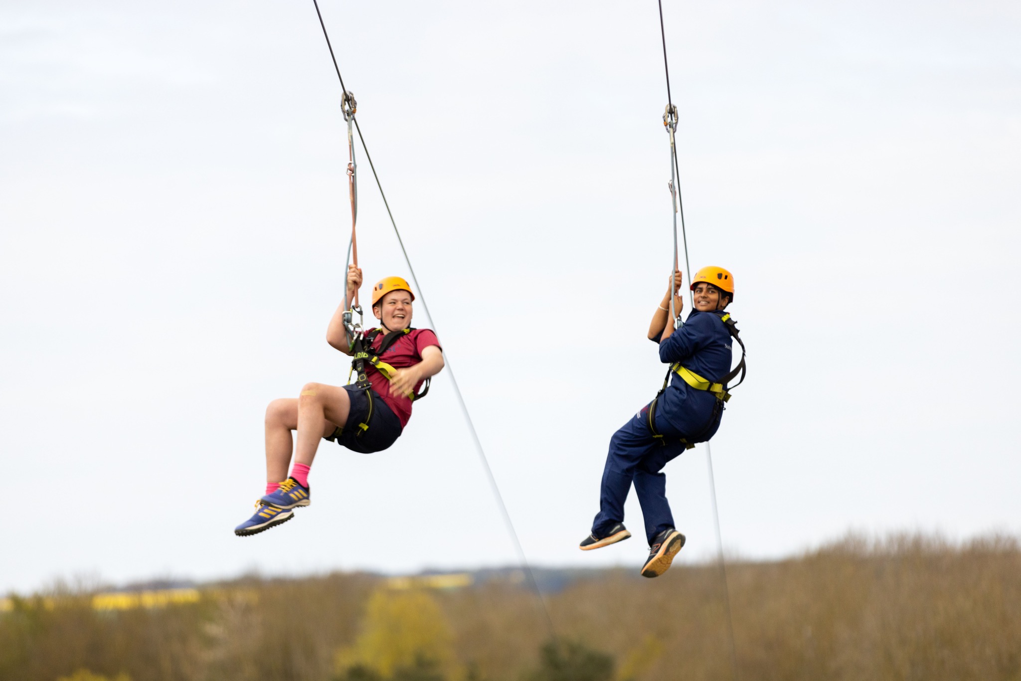 Two people zip-lining over scenic Yorkshire countryside