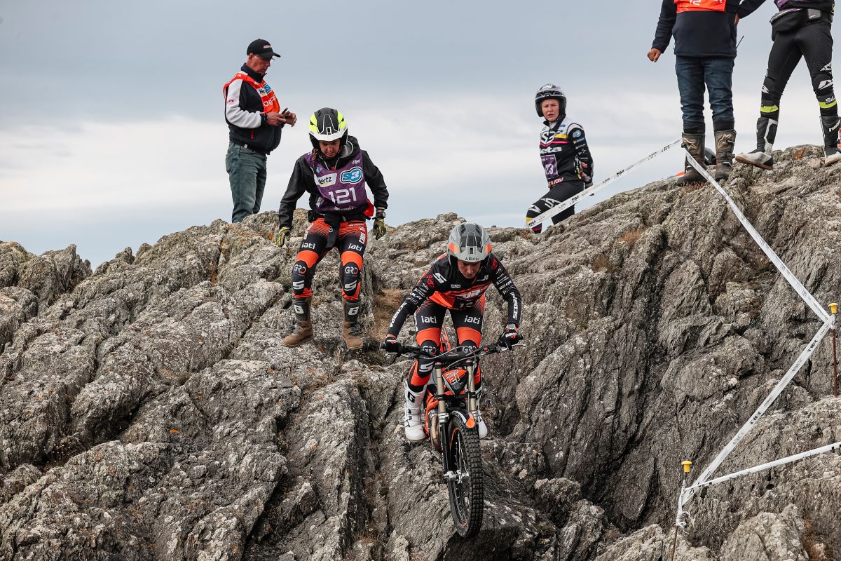 Mountain bikers in full gear navigating rocky terrain with spectators