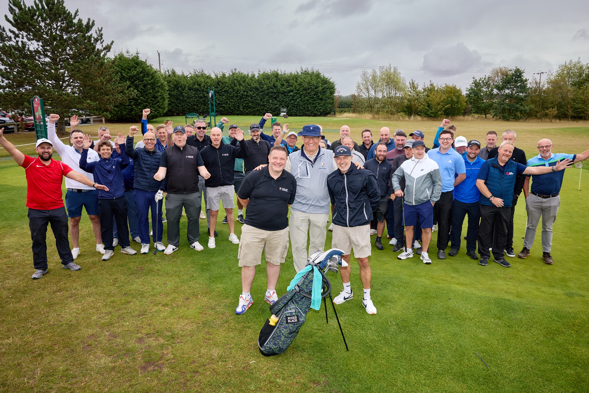 Group of golfers smiling and cheering on a green golf course