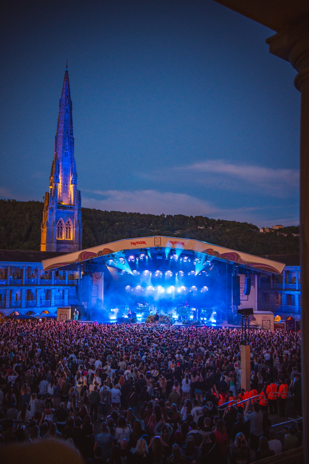 Crowd at outdoor concert with illuminated church spire