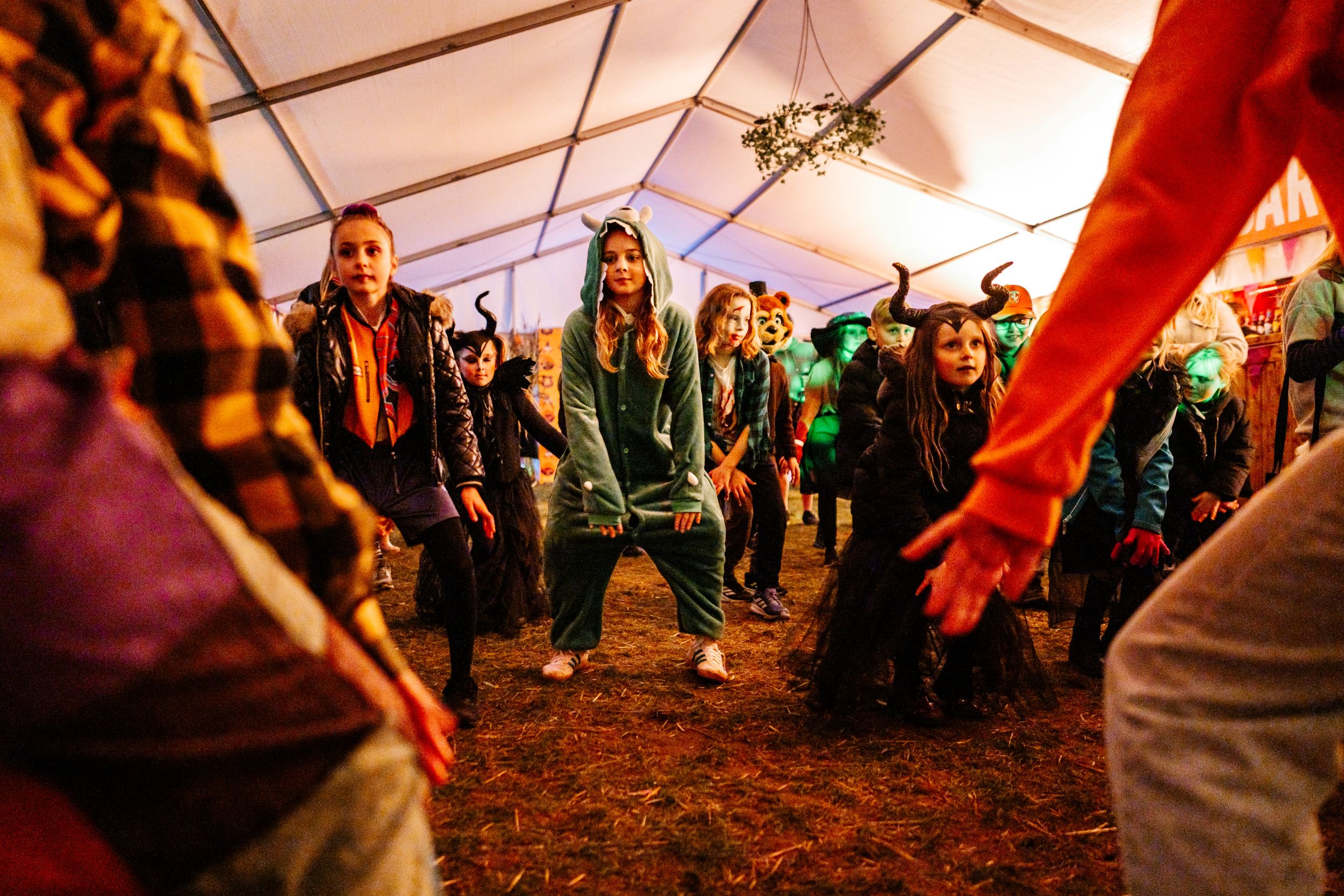 Children in Halloween costumes dancing inside a decorated tent