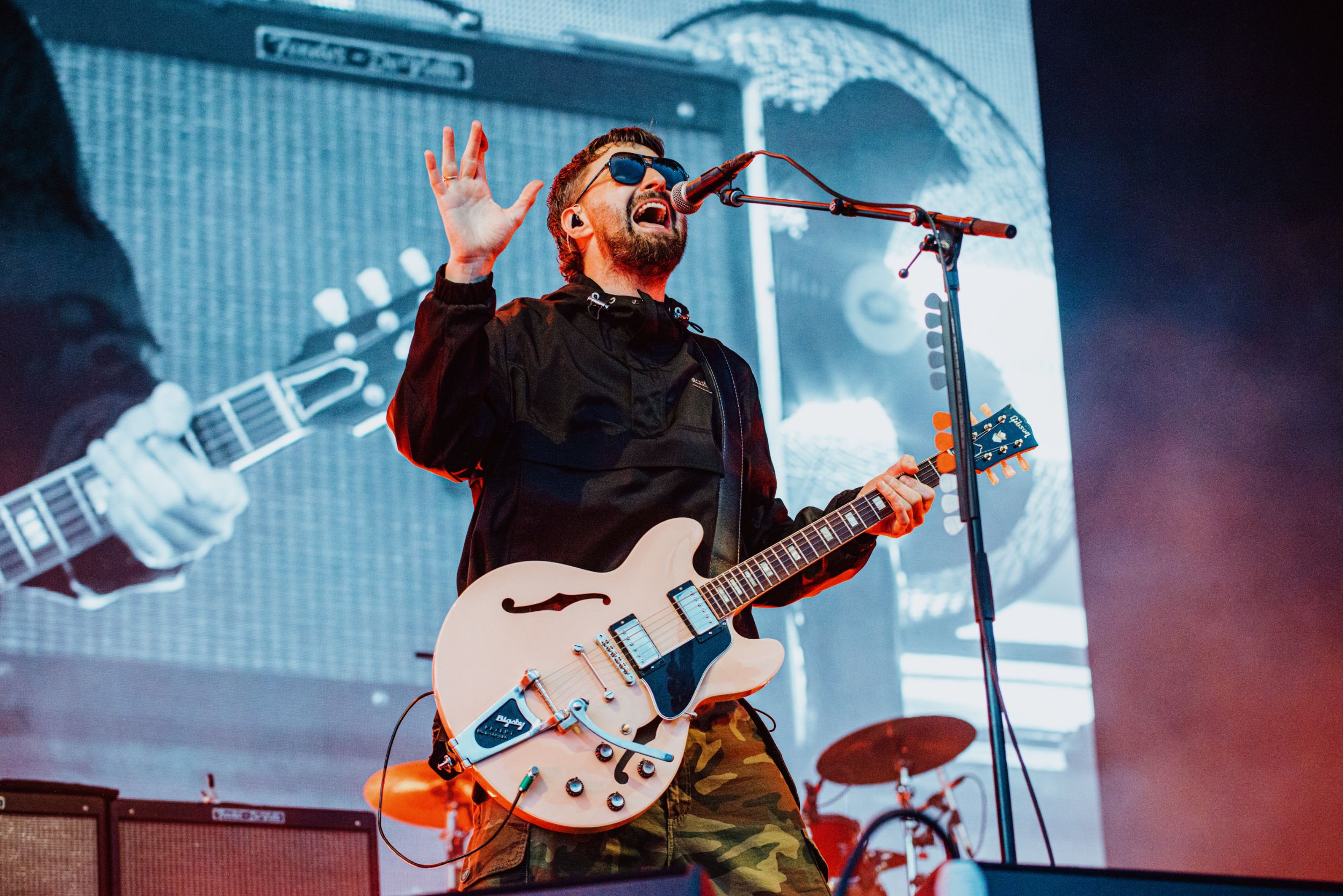 Musician performs with white electric guitar on stage