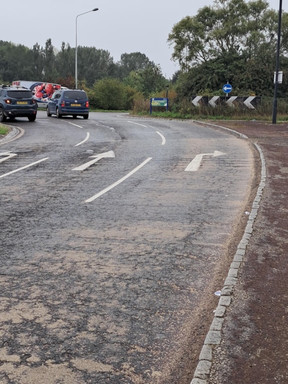 Roundabout with road signs and cars on a cloudy day