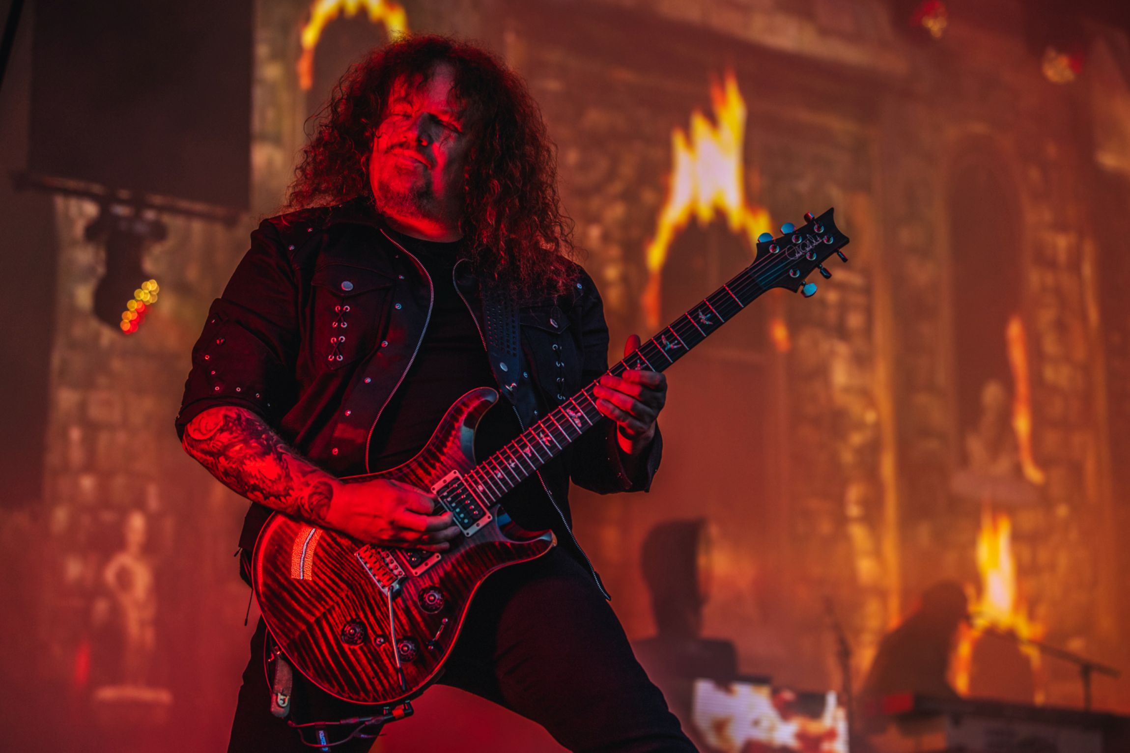 Guitarist with long hair playing electric guitar on stage
