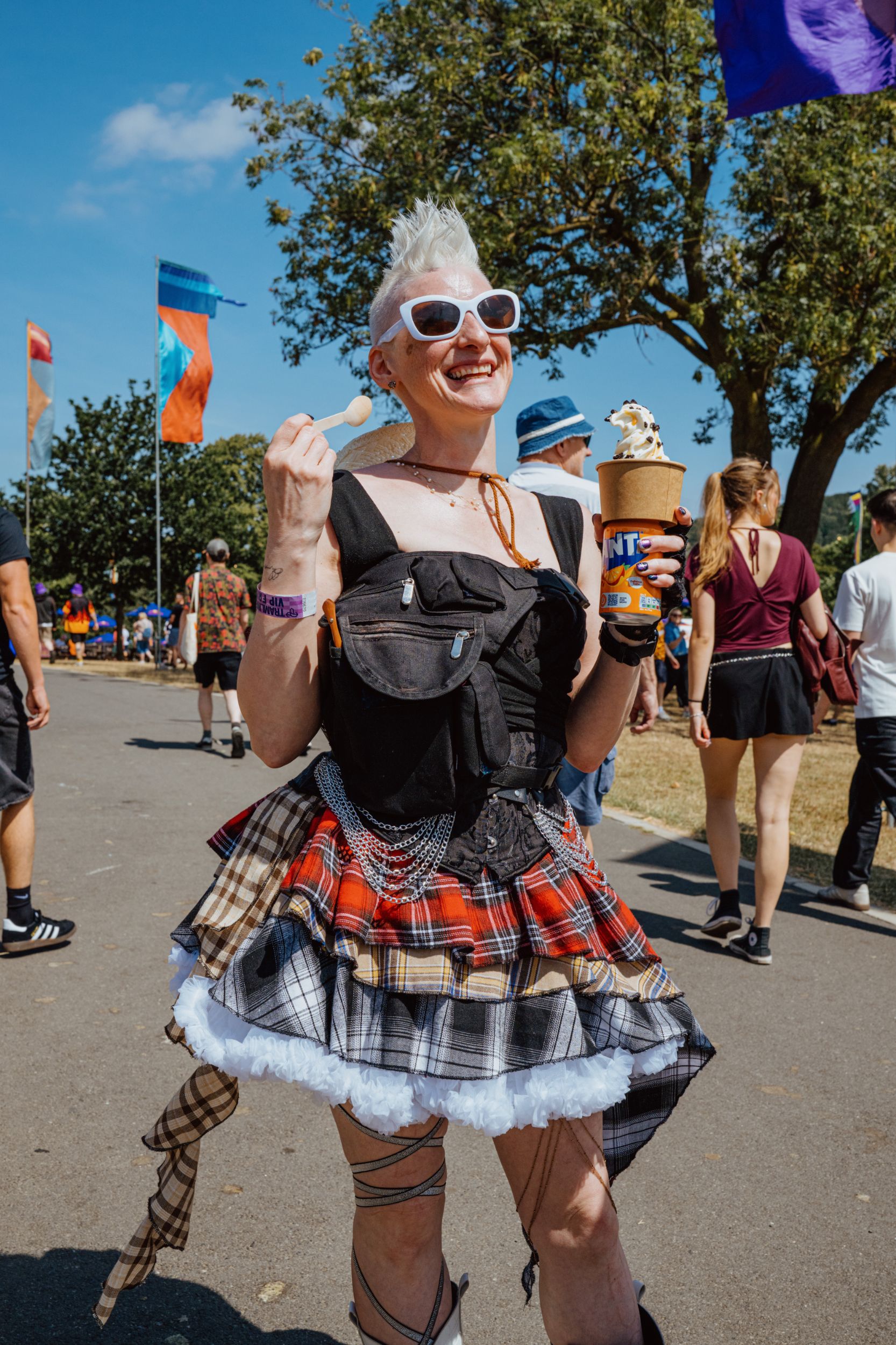 Smiling person in tartan skirt at outdoor festival with ice cream