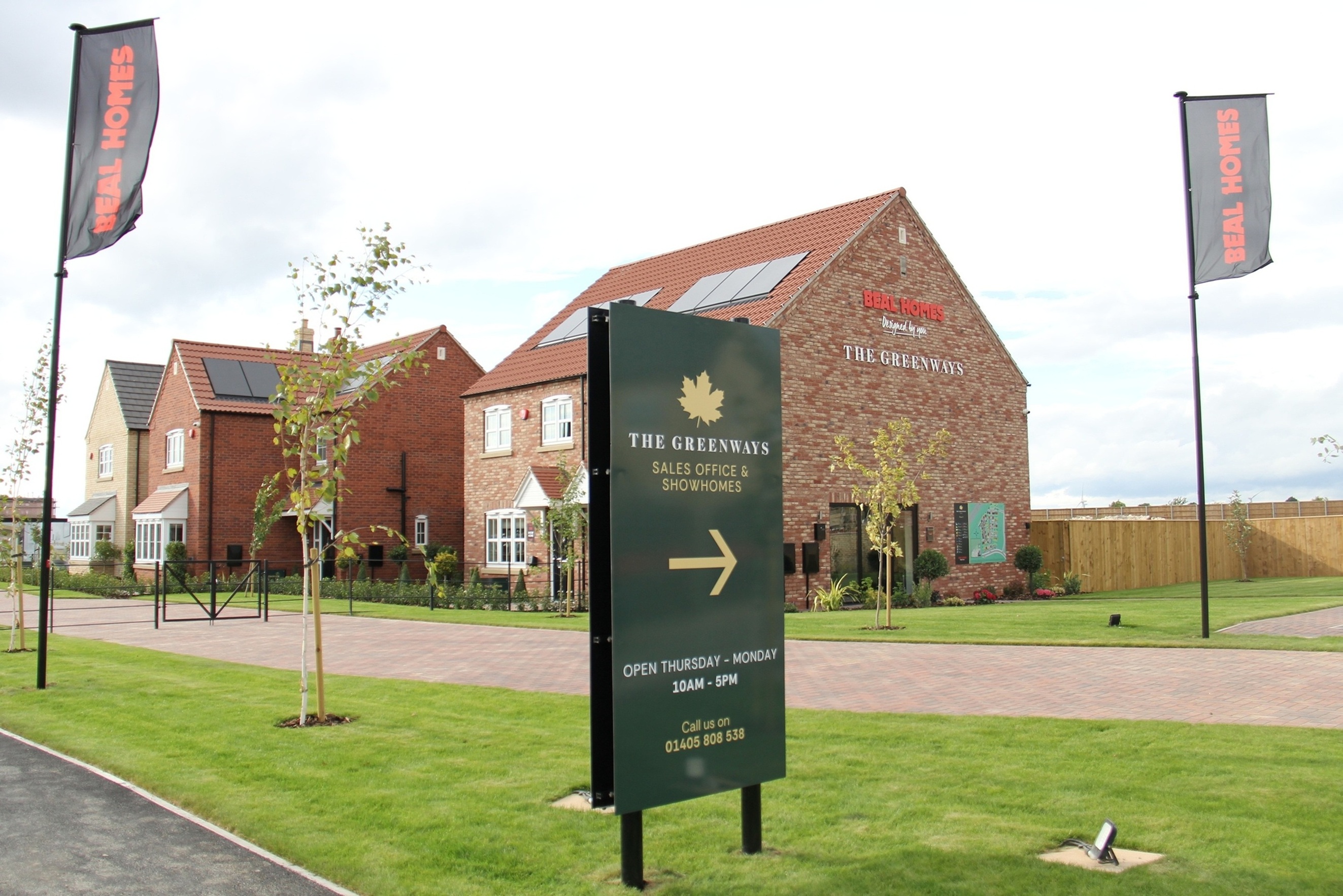 Red brick sales office with flags and green lawn