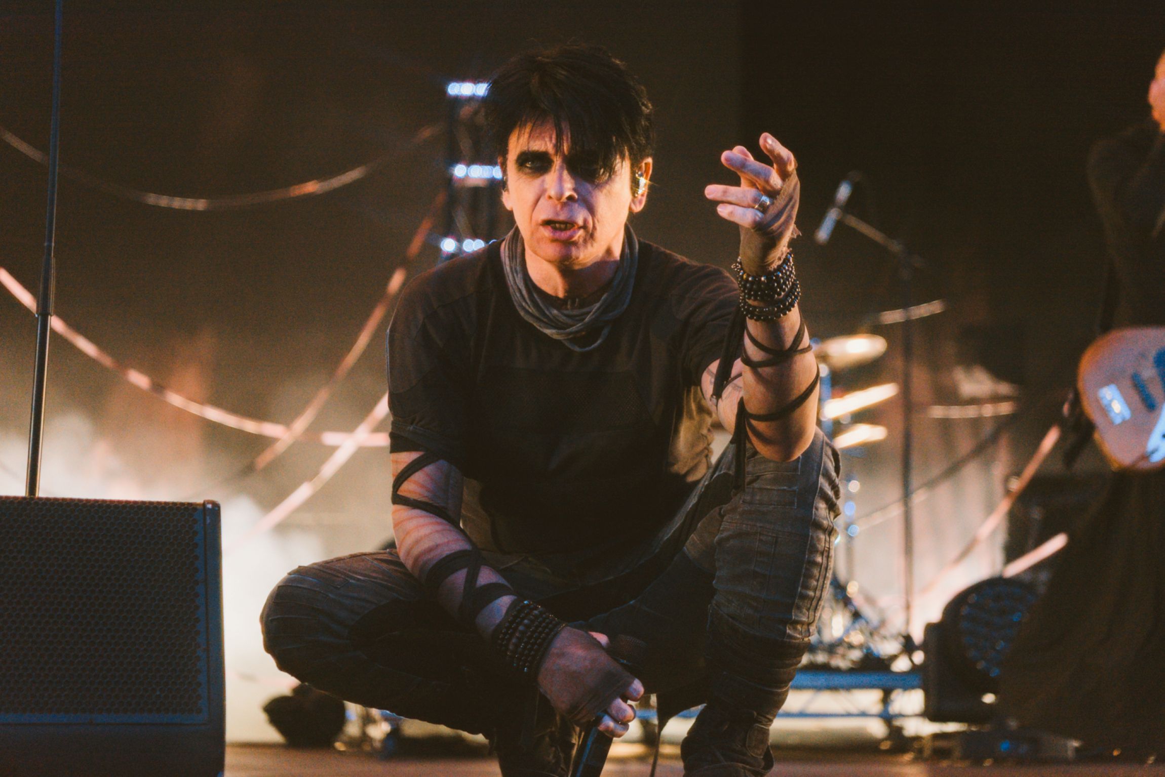 Performer in dark attire on stage with dramatic lighting
