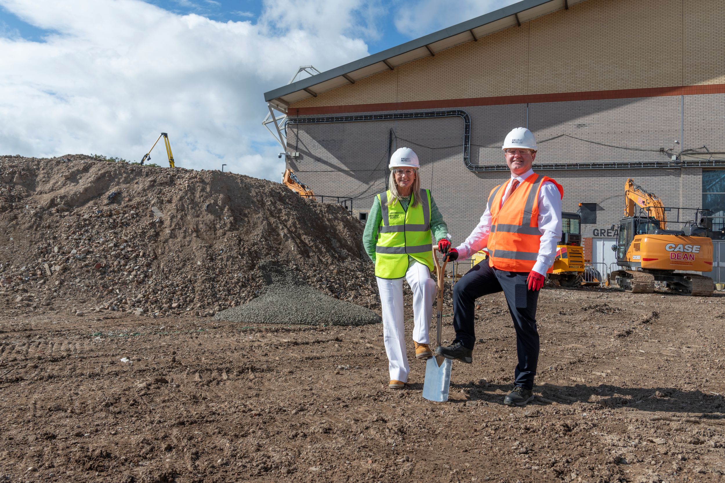 Two construction workers in high-vis jackets and helmets at a building site