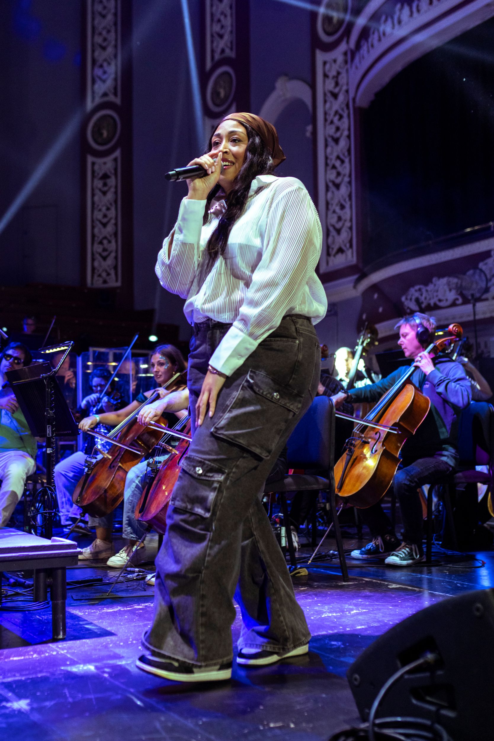Singer performing on stage with orchestra in ornate hall