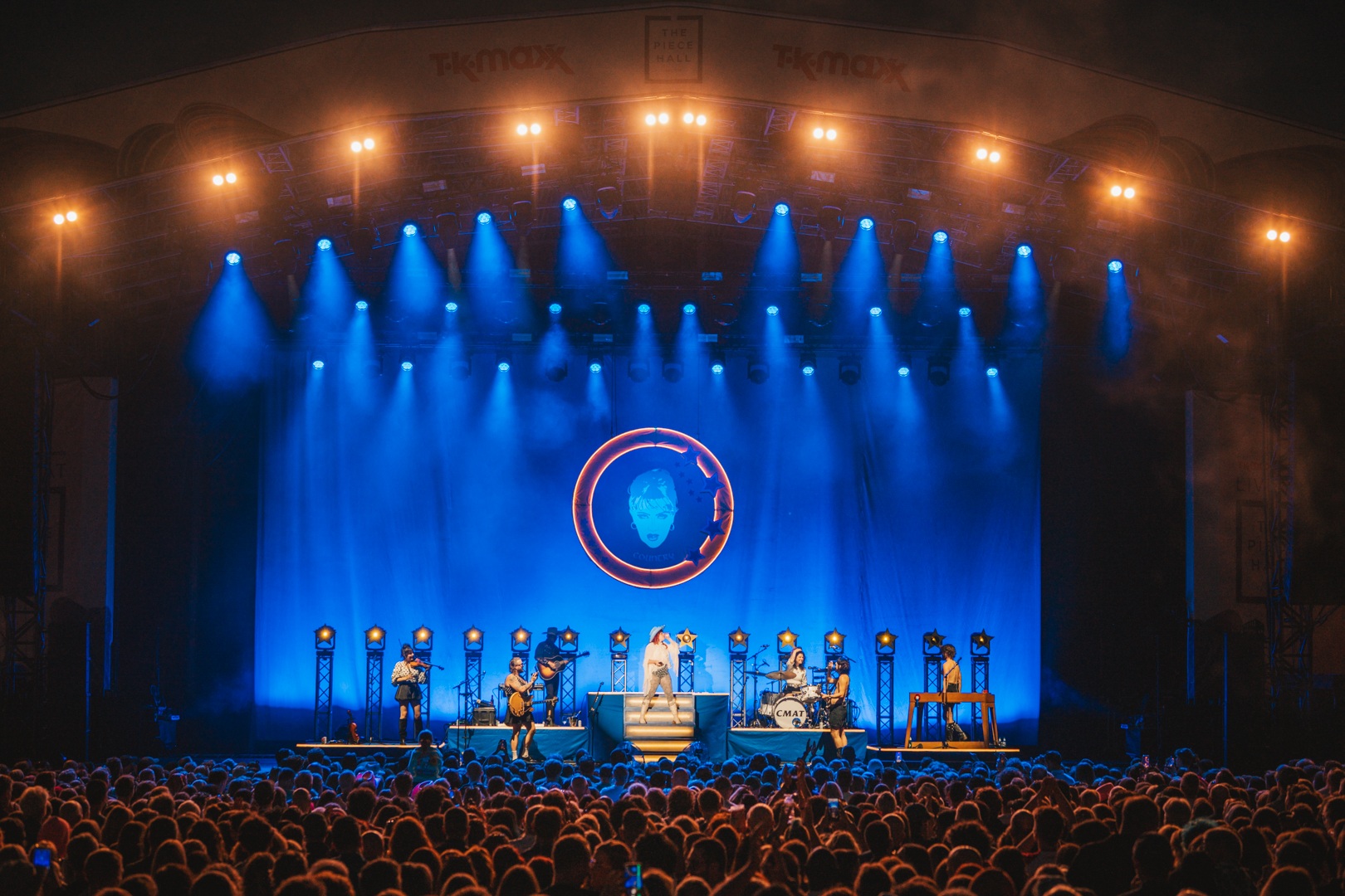 Outdoor concert with band performing under bright stage lights