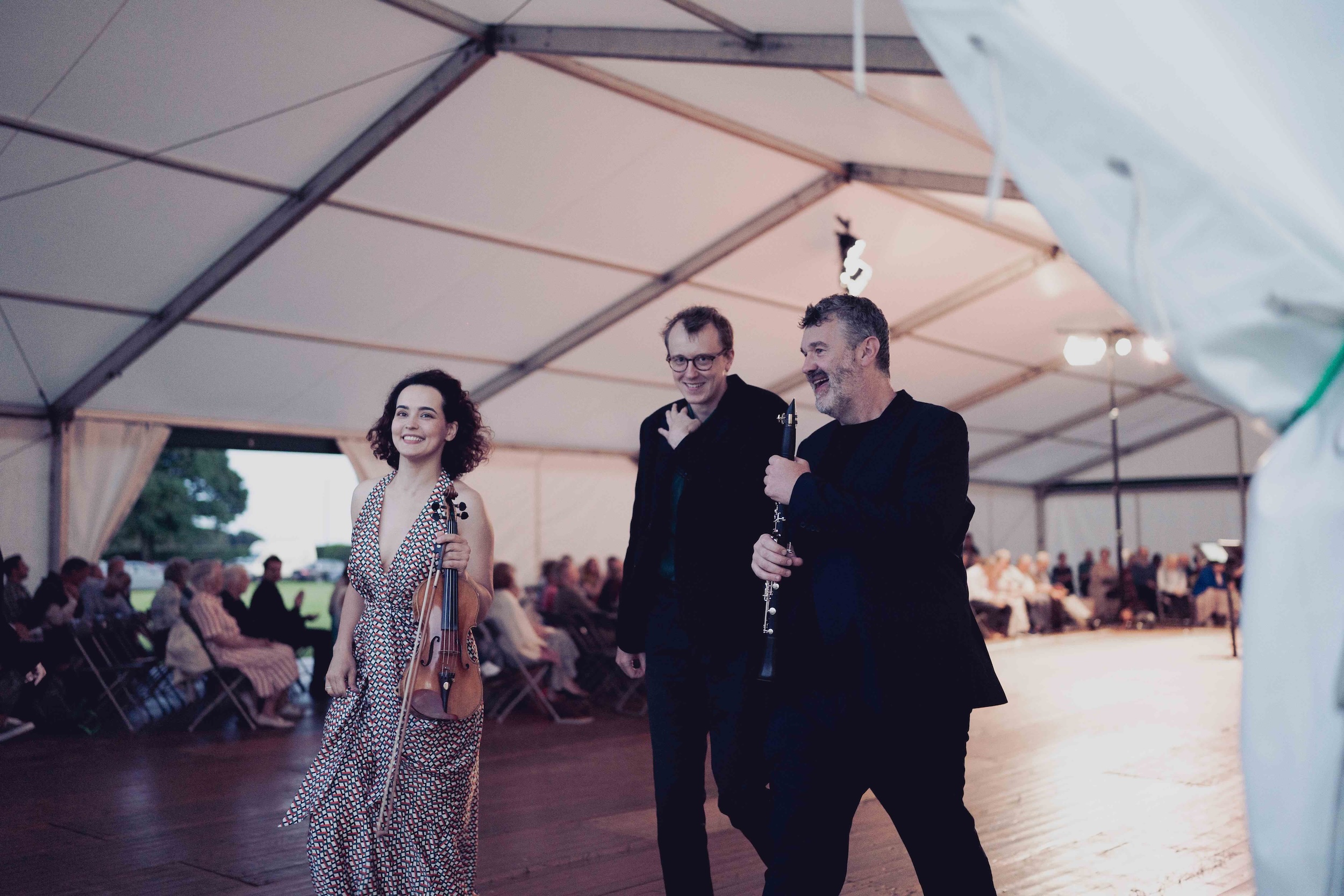 Musicians with violin and clarinet walking inside a marquee