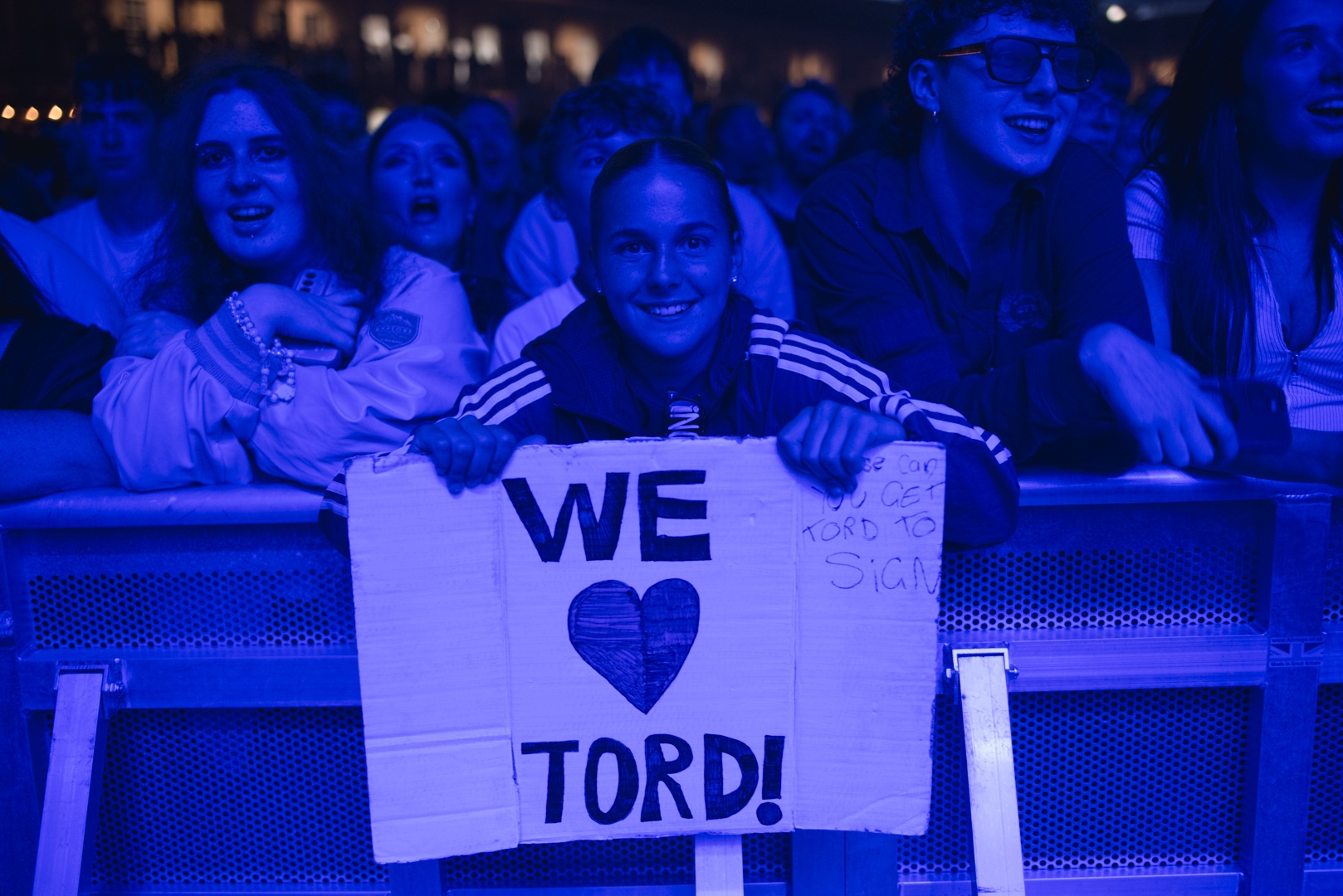 Concert audience with people holding a sign reading 'We Love Tord'