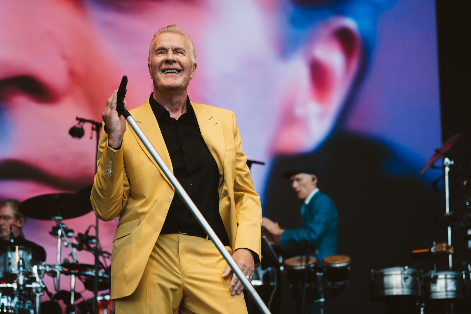 Smiling man in yellow suit performing on outdoor stage