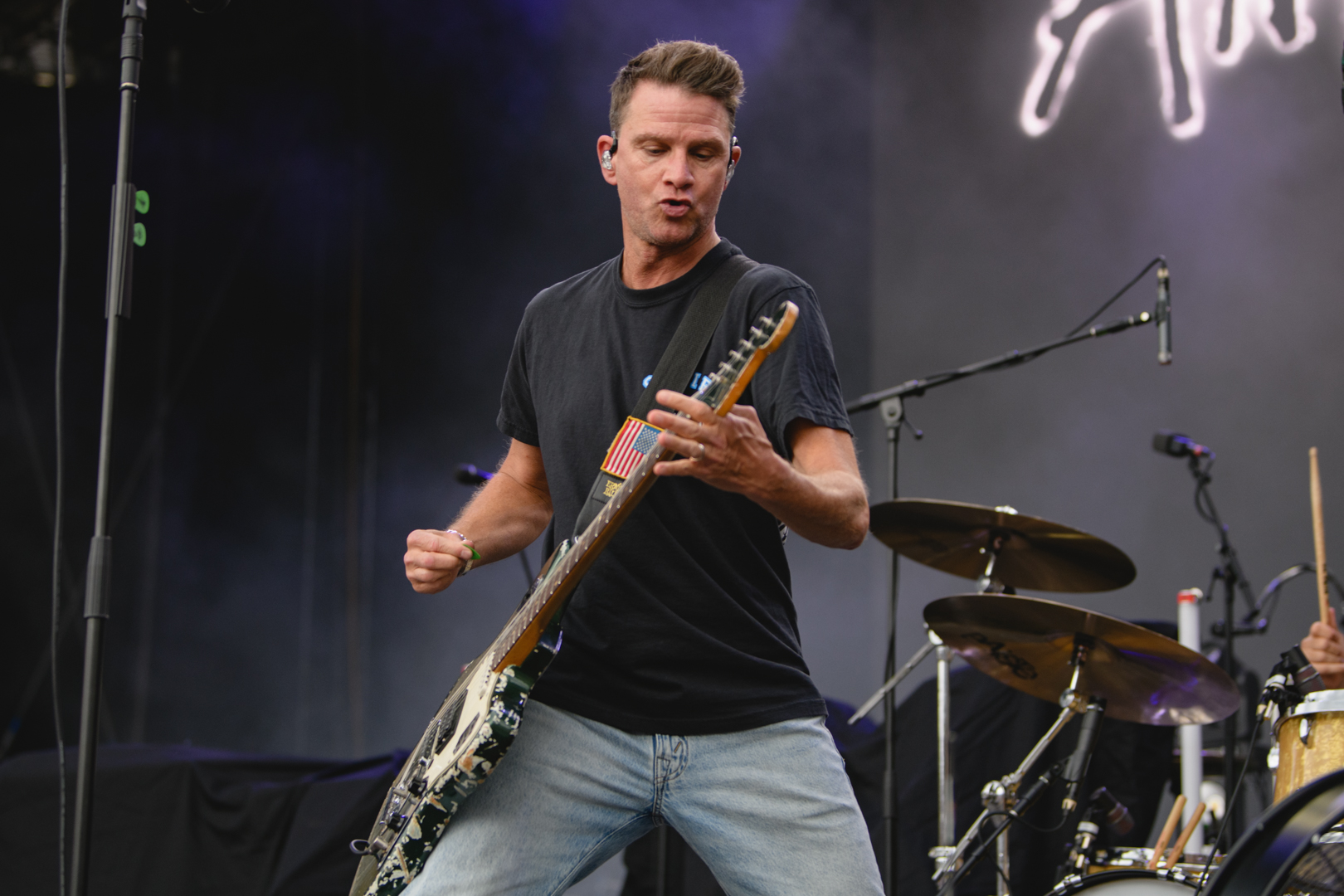 Guitarist performing energetically on stage with drum set