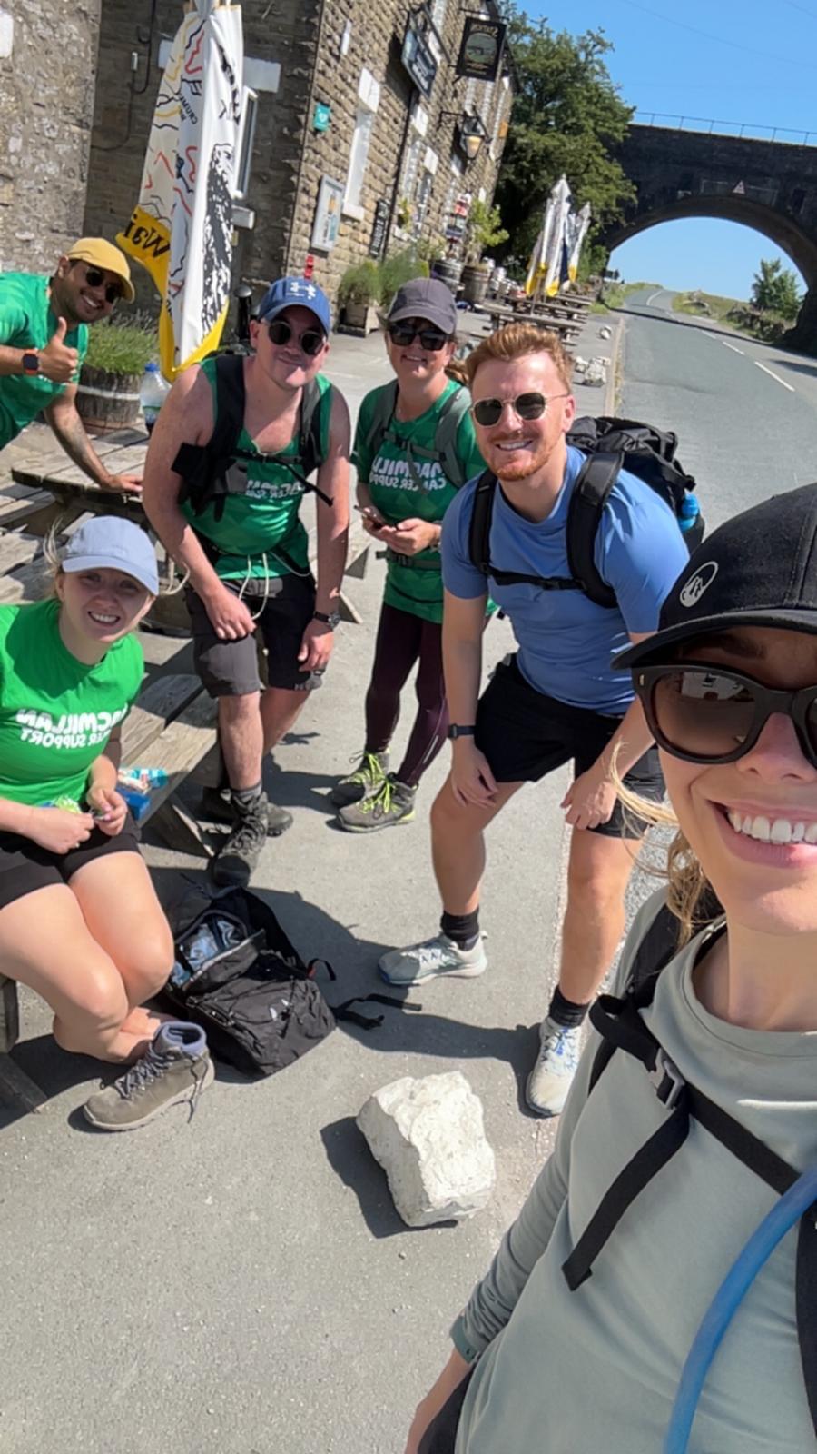 Group of hikers resting on a sunny day beside a stone bridge