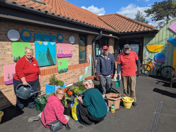Volunteers planting flowers outside a brick community centre