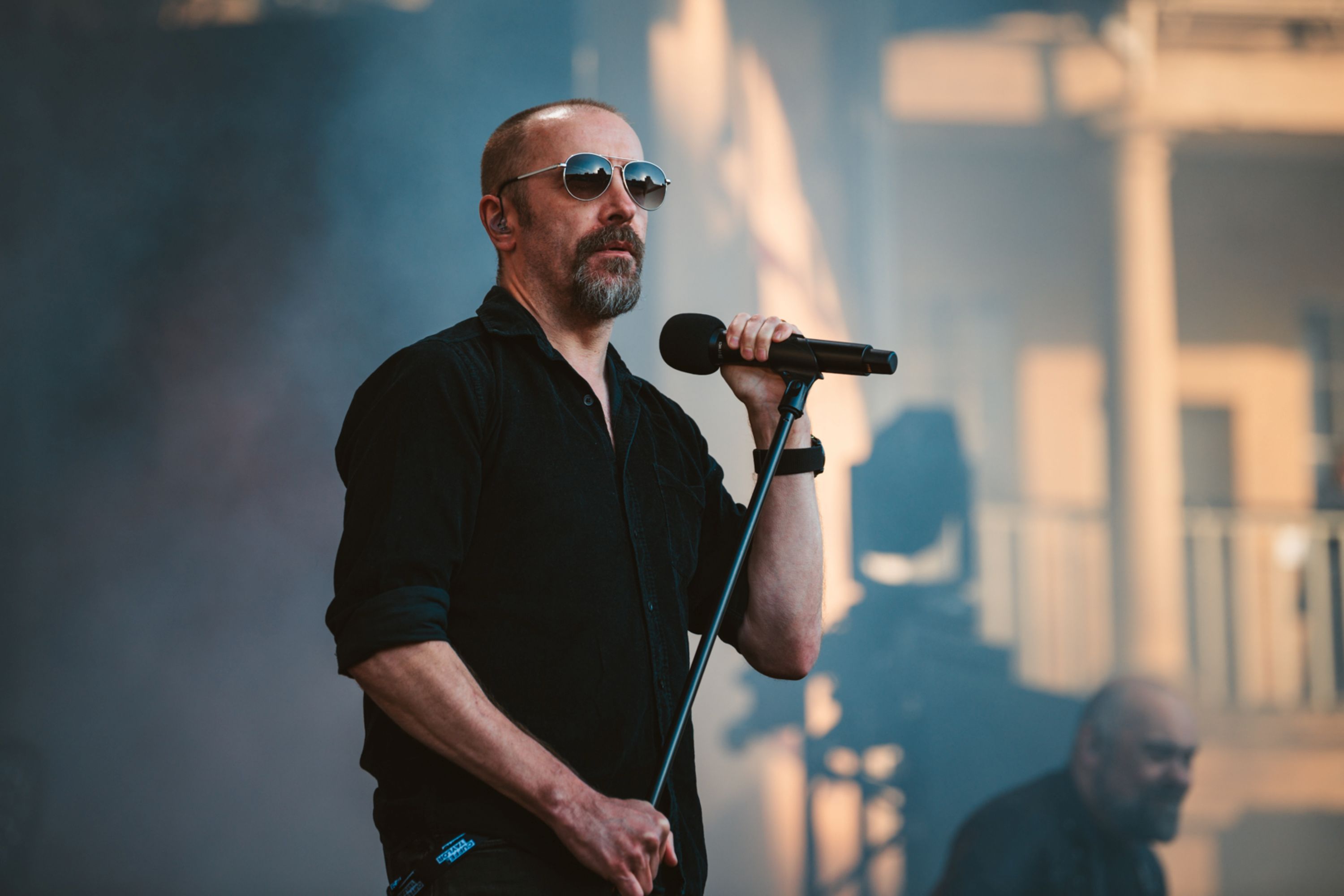 Male musician in sunglasses performing on stage with microphone